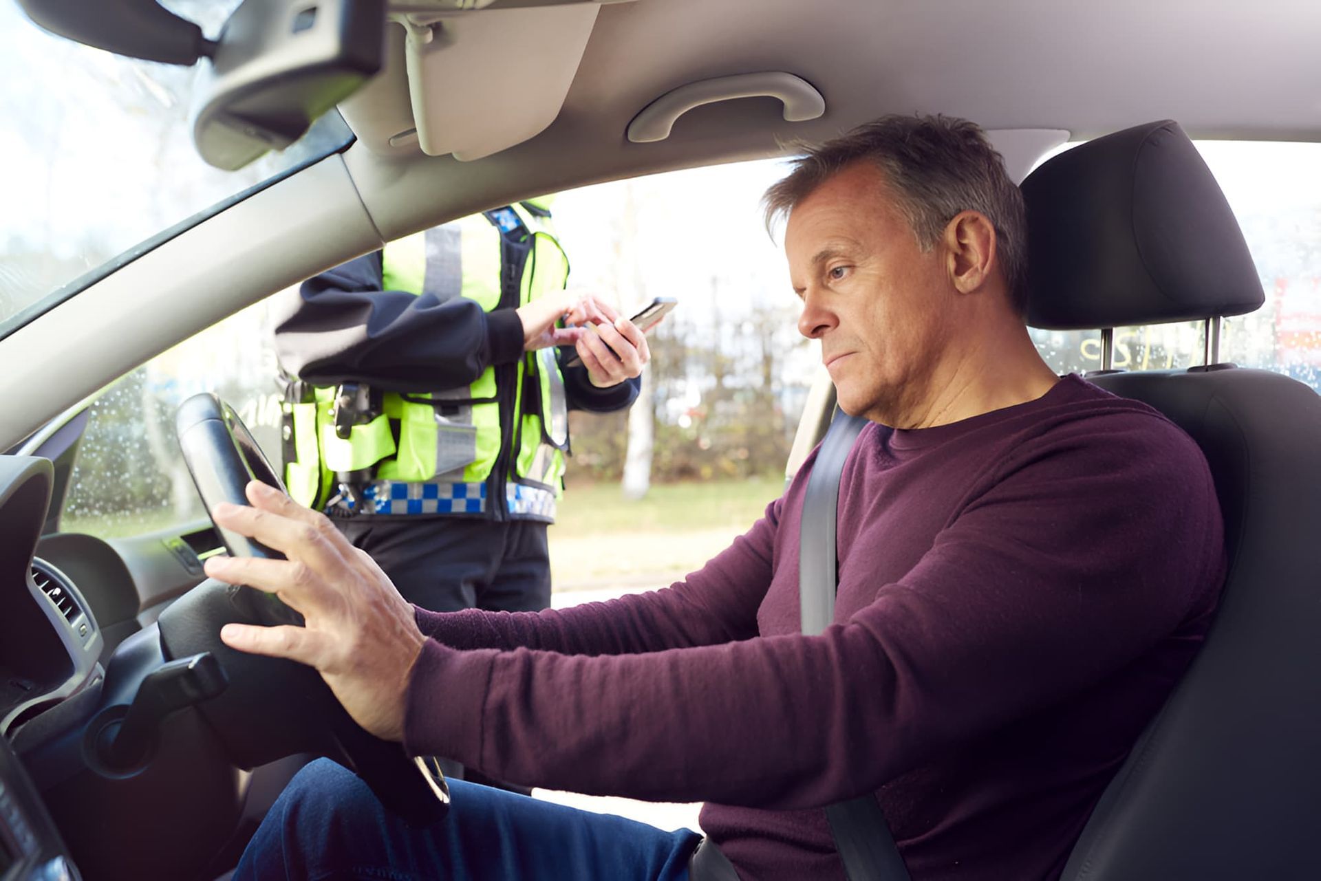 A Man Is Sitting In A Car Talking To A Police Officer — Cairns Criminal Lawyers In Gordonvale, QLD