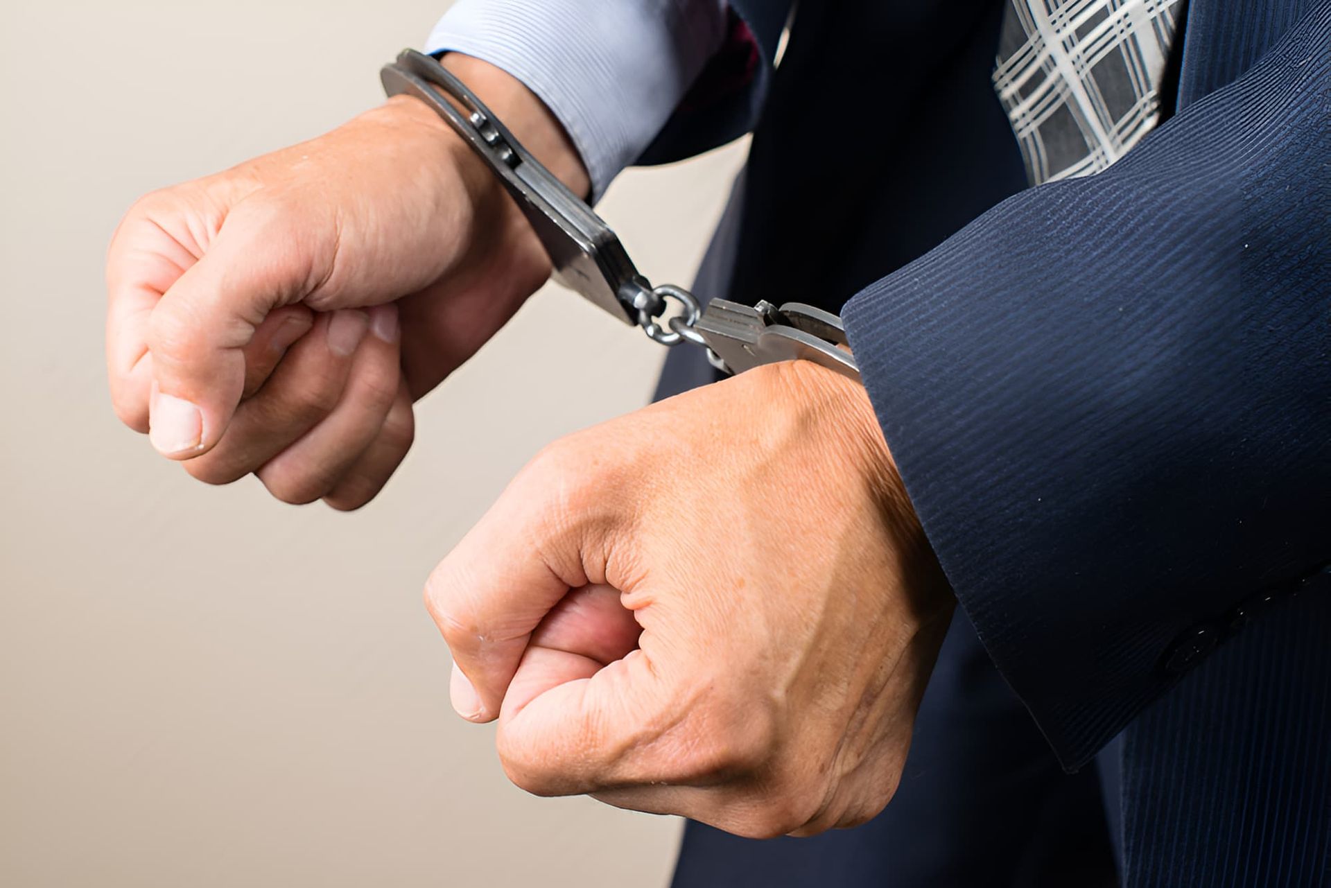 A Man In A Suit And Tie Is Wearing Handcuffs — Cairns Criminal Lawyers In Gordonvale, QLD