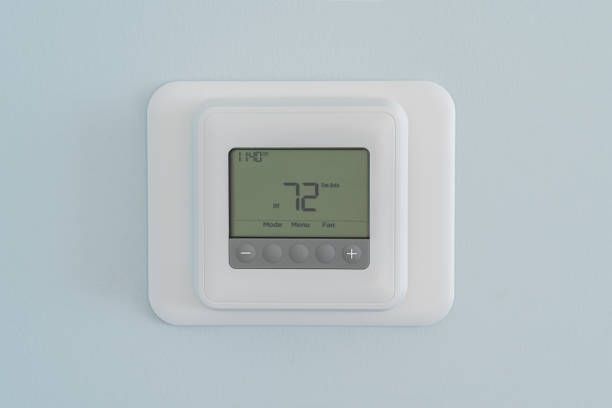 A digital thermostat is mounted on a wall.