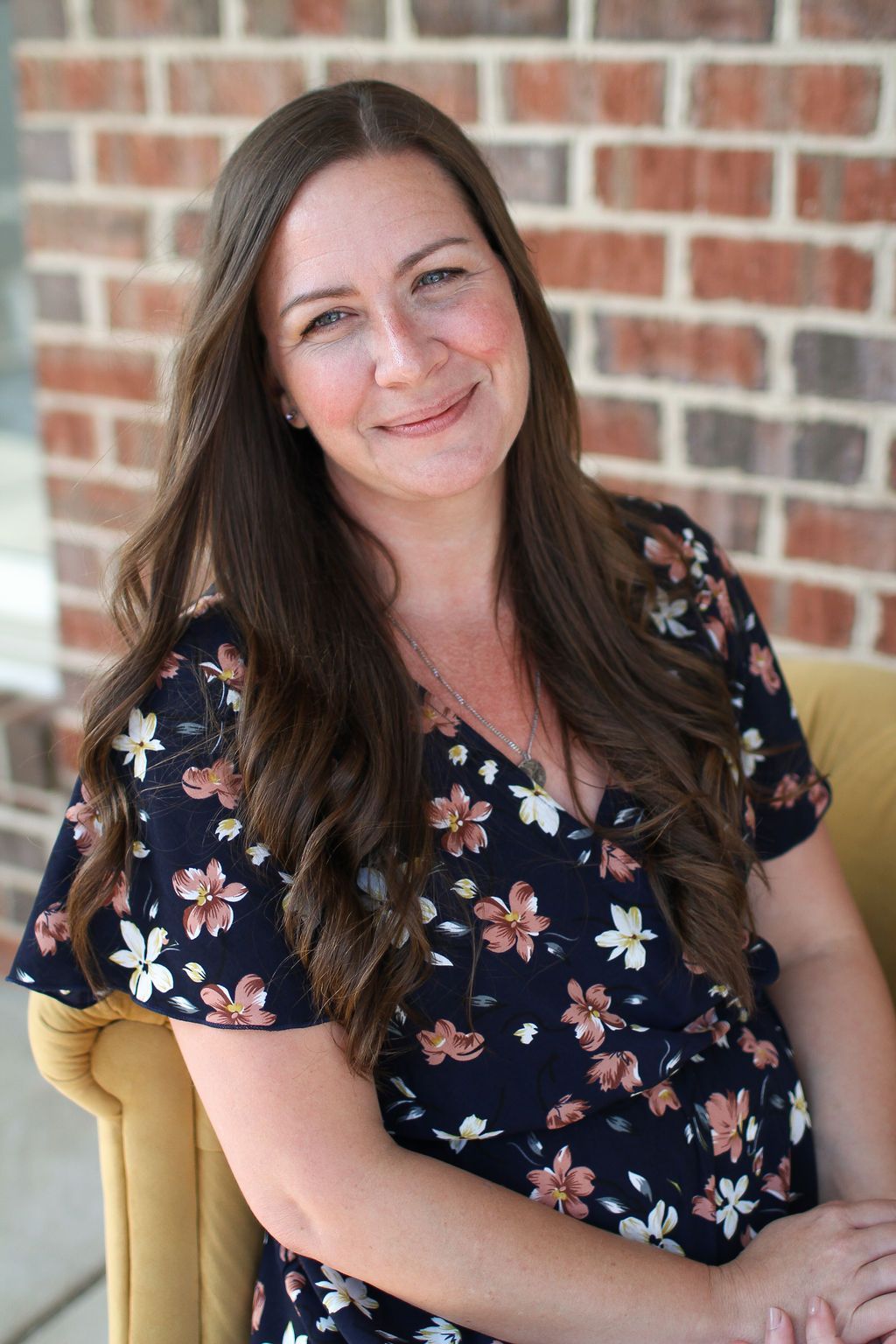 A woman with long hair is smiling for the camera while sitting in a chair.
