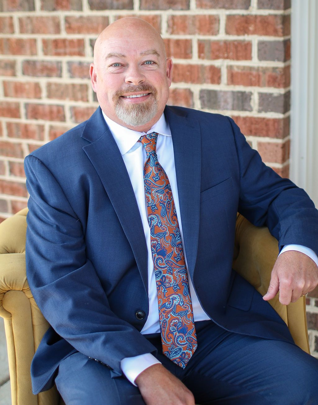A man in a suit and white shirt is smiling for the camera.