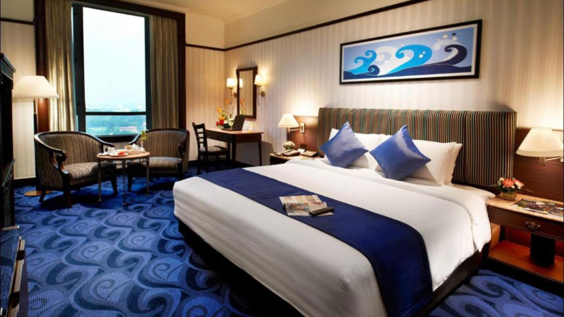 Hotel room with a large bed, blue carpet, and a window with a city view.