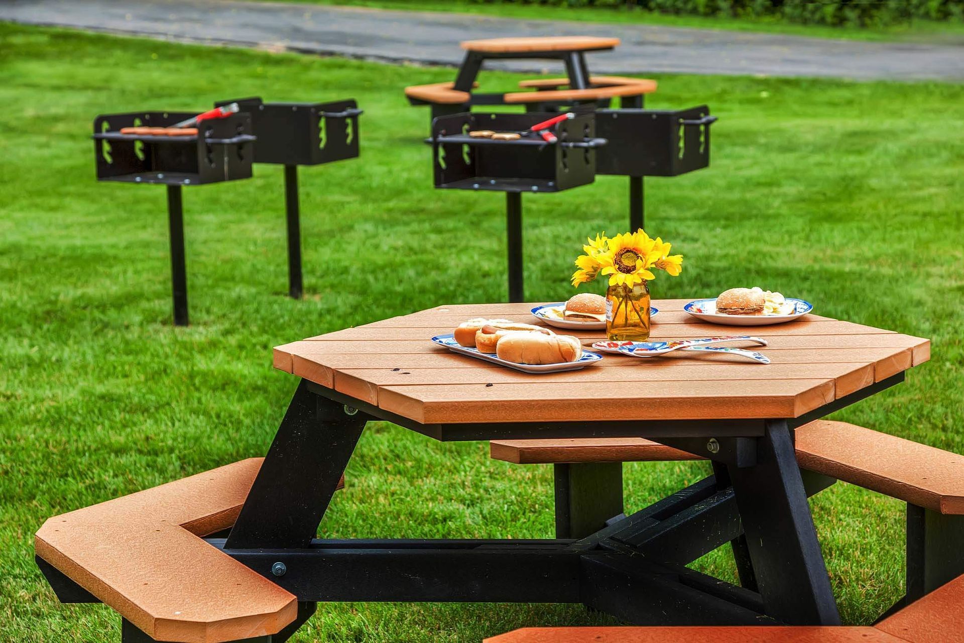 Outdoor community picnic area with grills and a wooden table set for a meal.