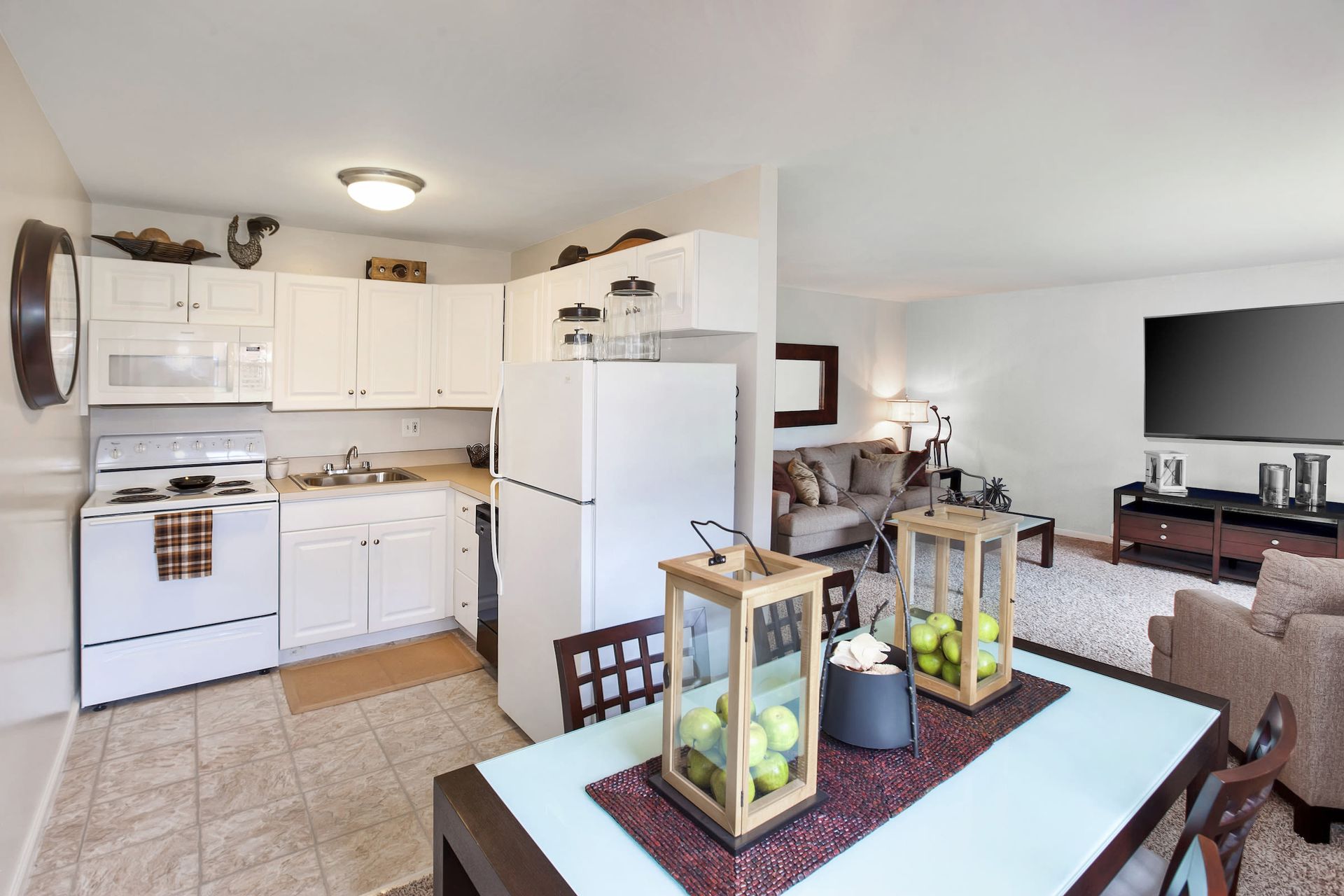 Open-concept kitchen with white cabinets, fridge, stove, and adjacent dining area.