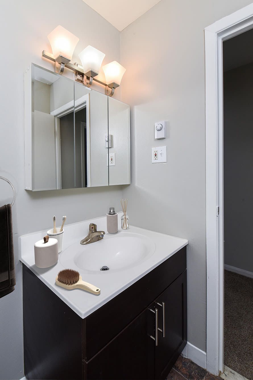 Bathroom vanity with sink, mirror cabinet, and a bright three-light fixture.