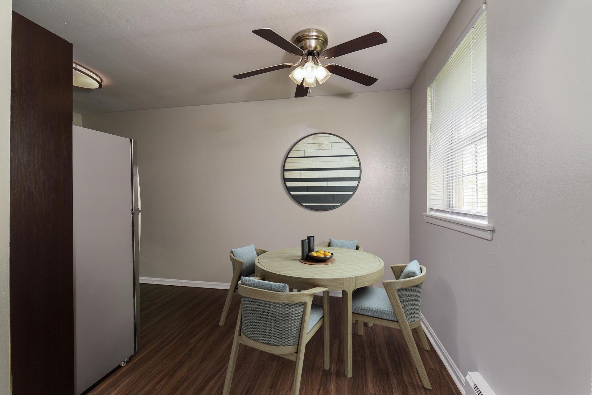 Small apartment dining nook with a round table, four chairs, a ceiling fan, and window blinds.