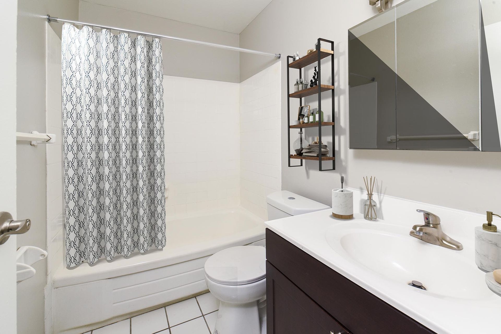 Bathroom with tub/shower, toilet, and dark wood vanity with a mirrored cabinet.