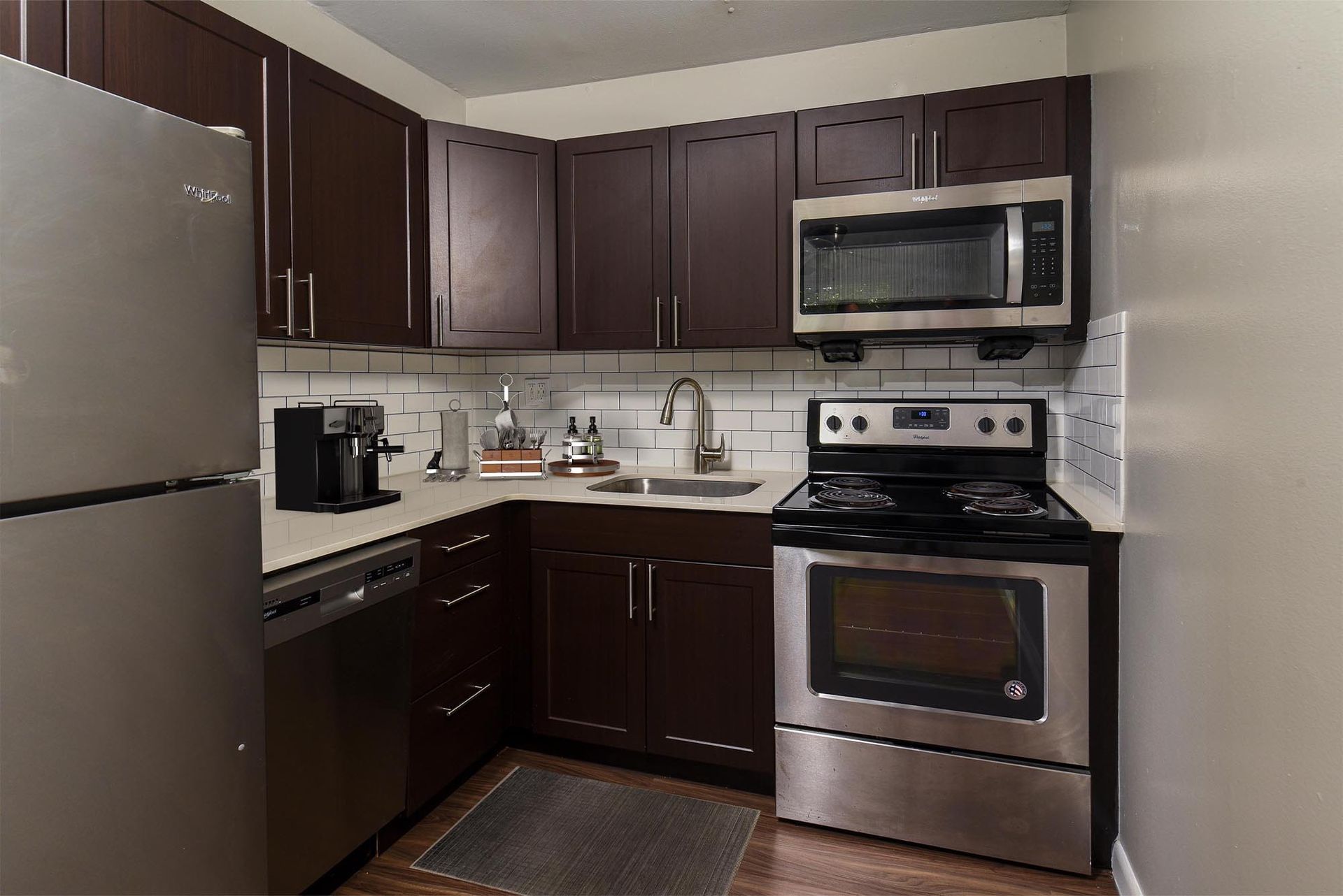 Compact kitchen with dark wood cabinets and stainless steel appliances.