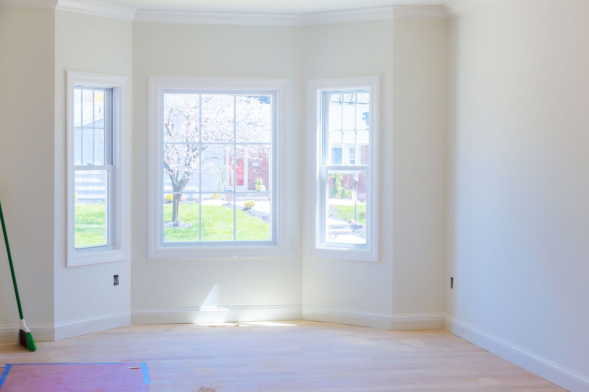 Bright empty room with bay windows, white walls, and sunlight on hardwood floor