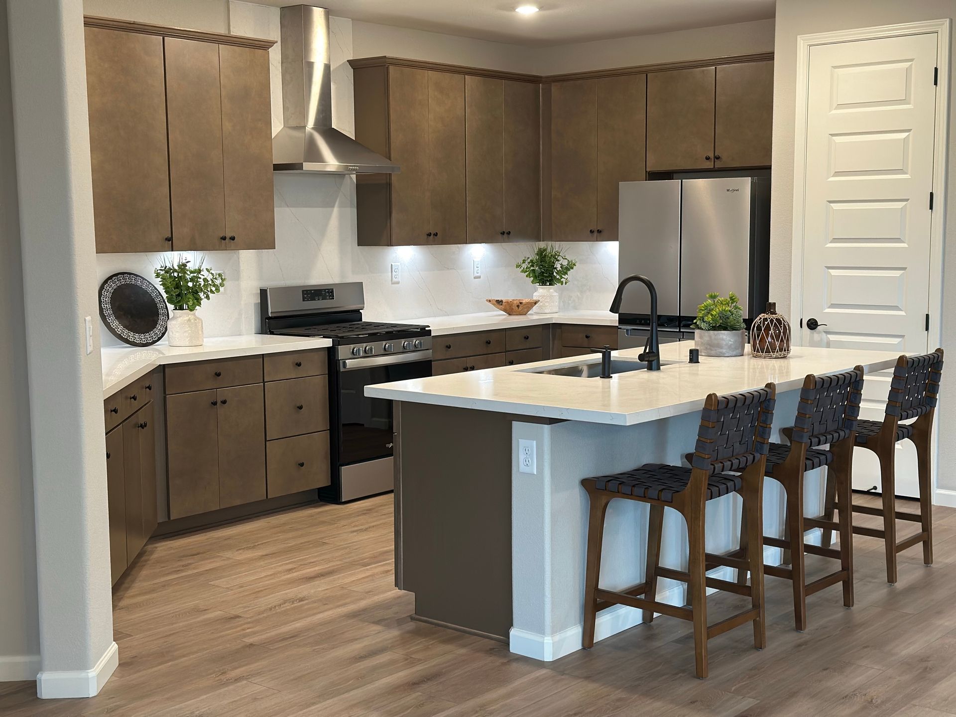 Modern kitchen with wood cabinets, island, stainless steel appliances, and four bar stools