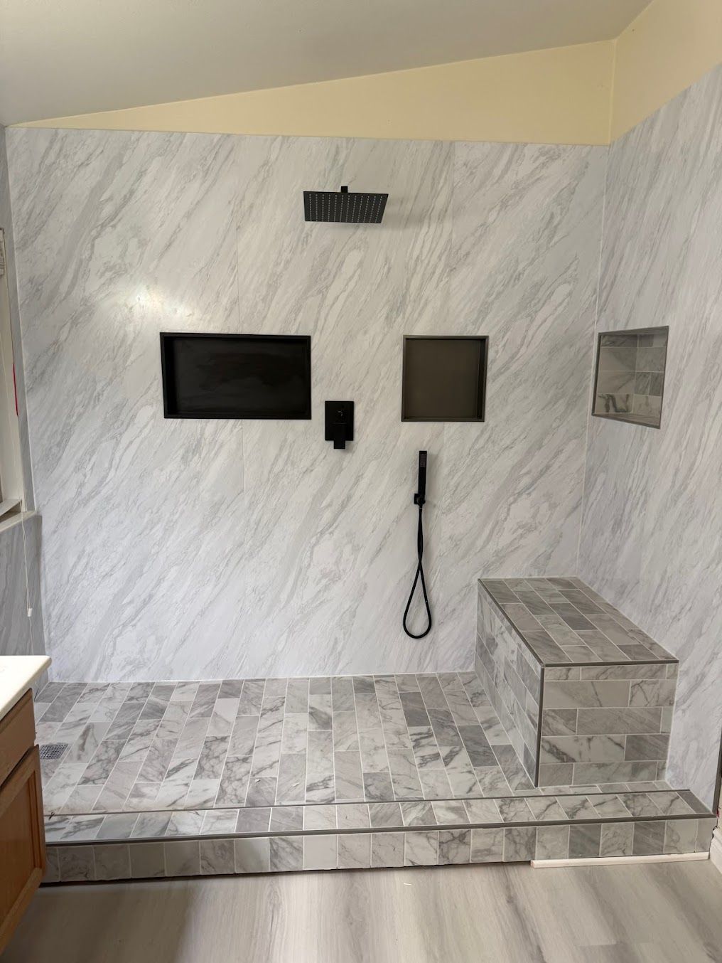 Marble-tiled bathroom with a walk-in shower, wall fixtures, and a raised step.