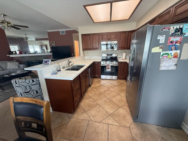 Modern kitchen with dark wood cabinets, island, stainless fridge, and beige tile floor