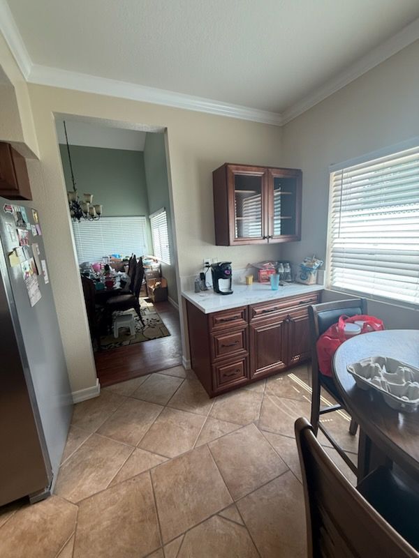 Kitchen with tan tile floor, wood cabinets, countertop appliances, and window blinds.