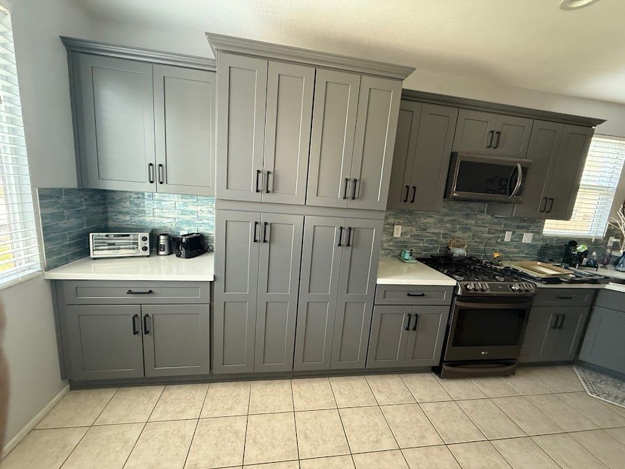 Modern kitchen with gray cabinets, tiled floor, and stainless steel appliances