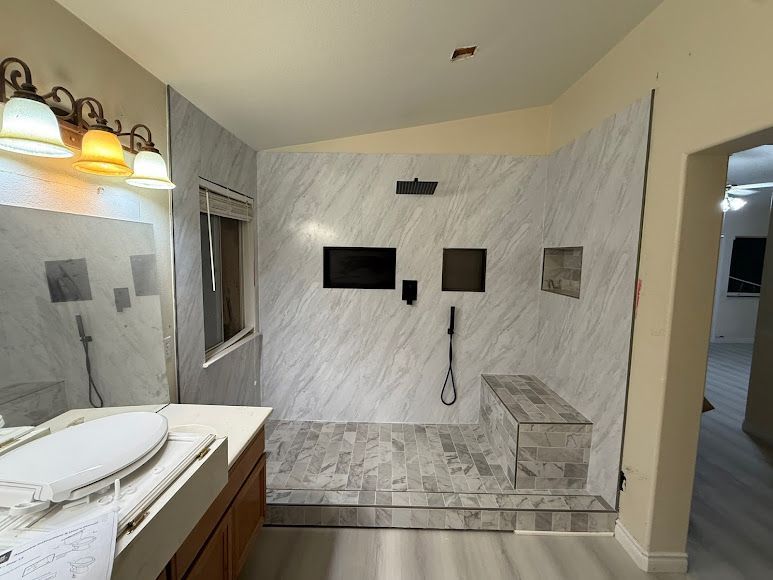 Marble-tiled bathroom with double sink vanity, lit mirror, and walk-in shower niche