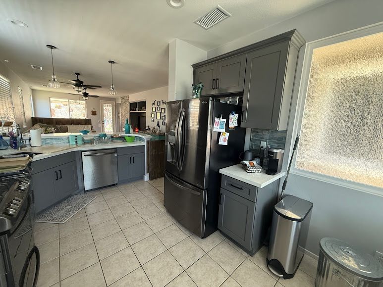Modern kitchen with gray cabinets, black appliances, tiled floor, and a windowed breakfast nook.