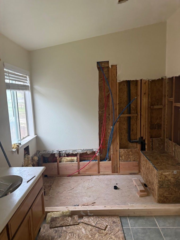 Kitchen under renovation with exposed walls, plumbing, and unfinished flooring