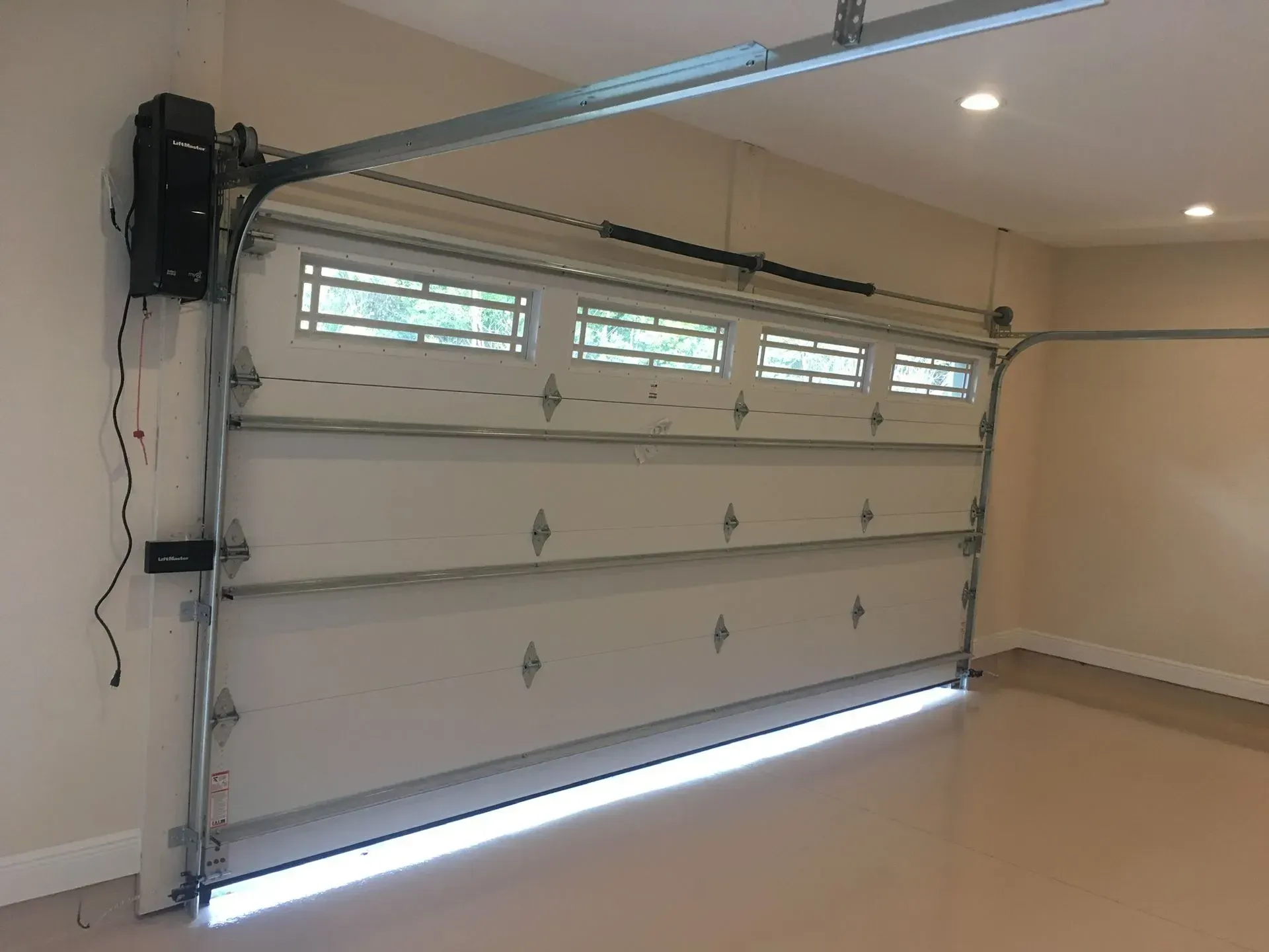 White garage door partially open with automatic opener.