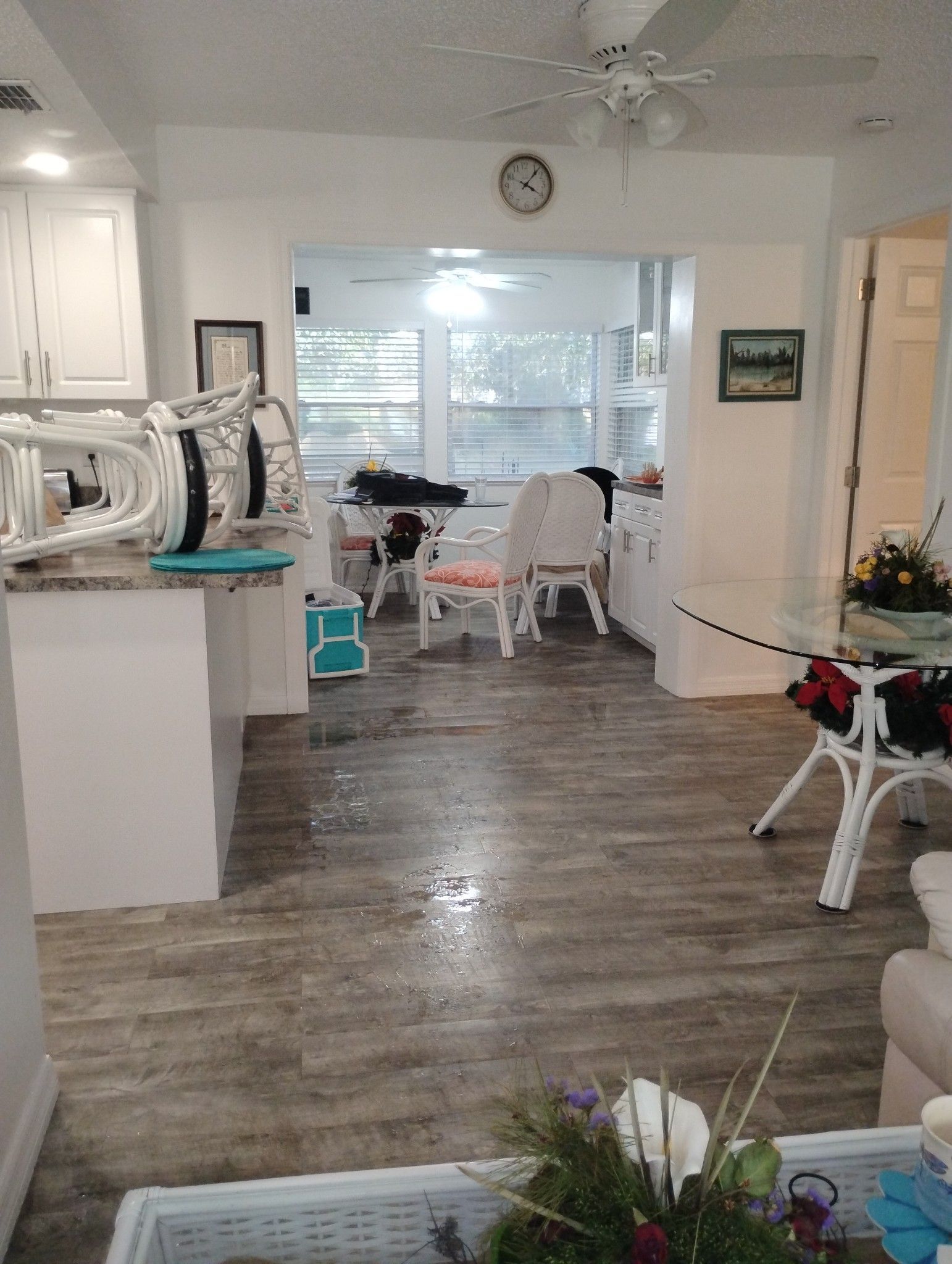 A living room with a table and chairs and a clock on the wall.