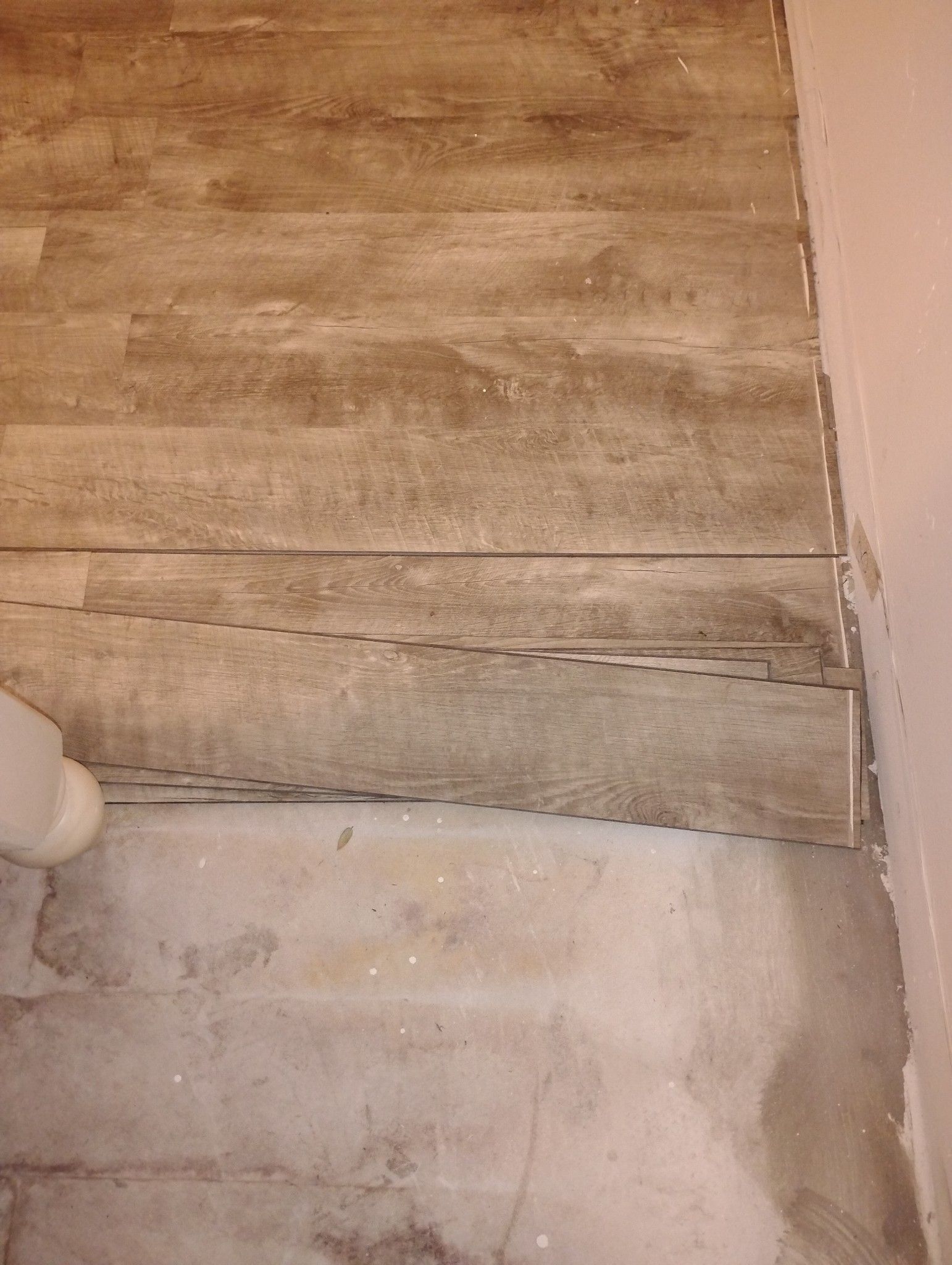 A close up of a wooden floor next to a toilet.