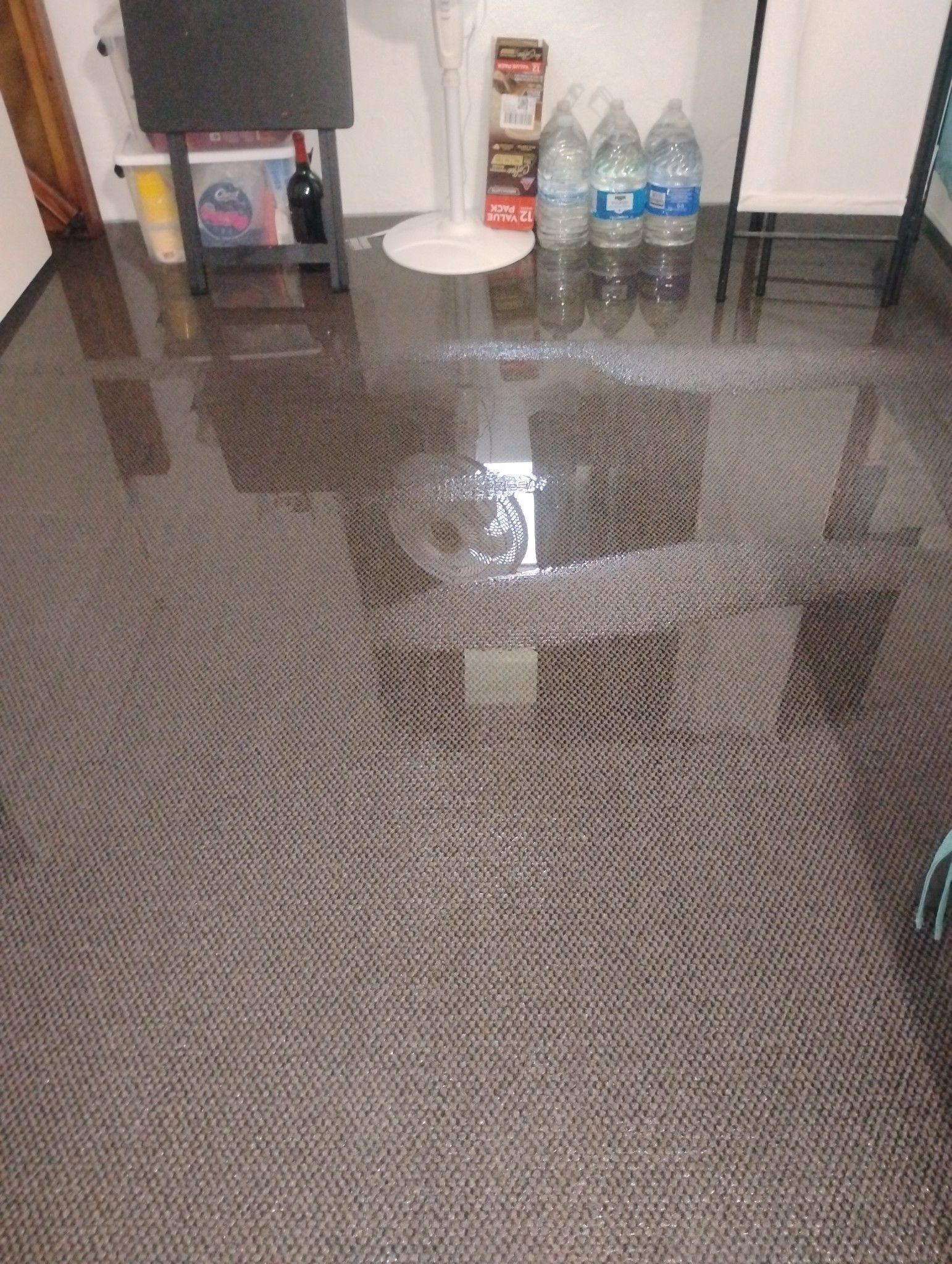 A room with a flooded floor and water bottles on the floor.