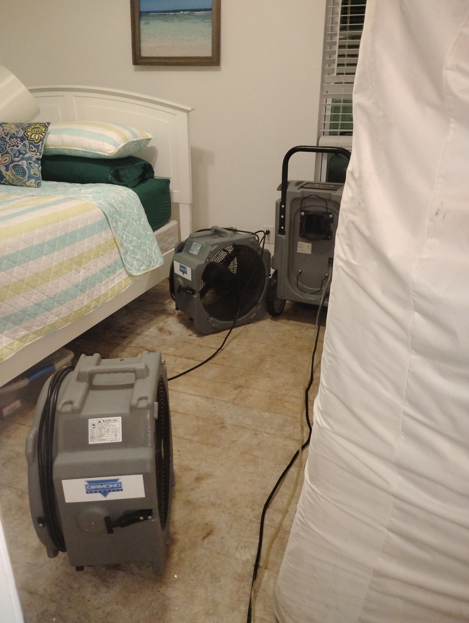 A bedroom with a bed and two fans on the floor.