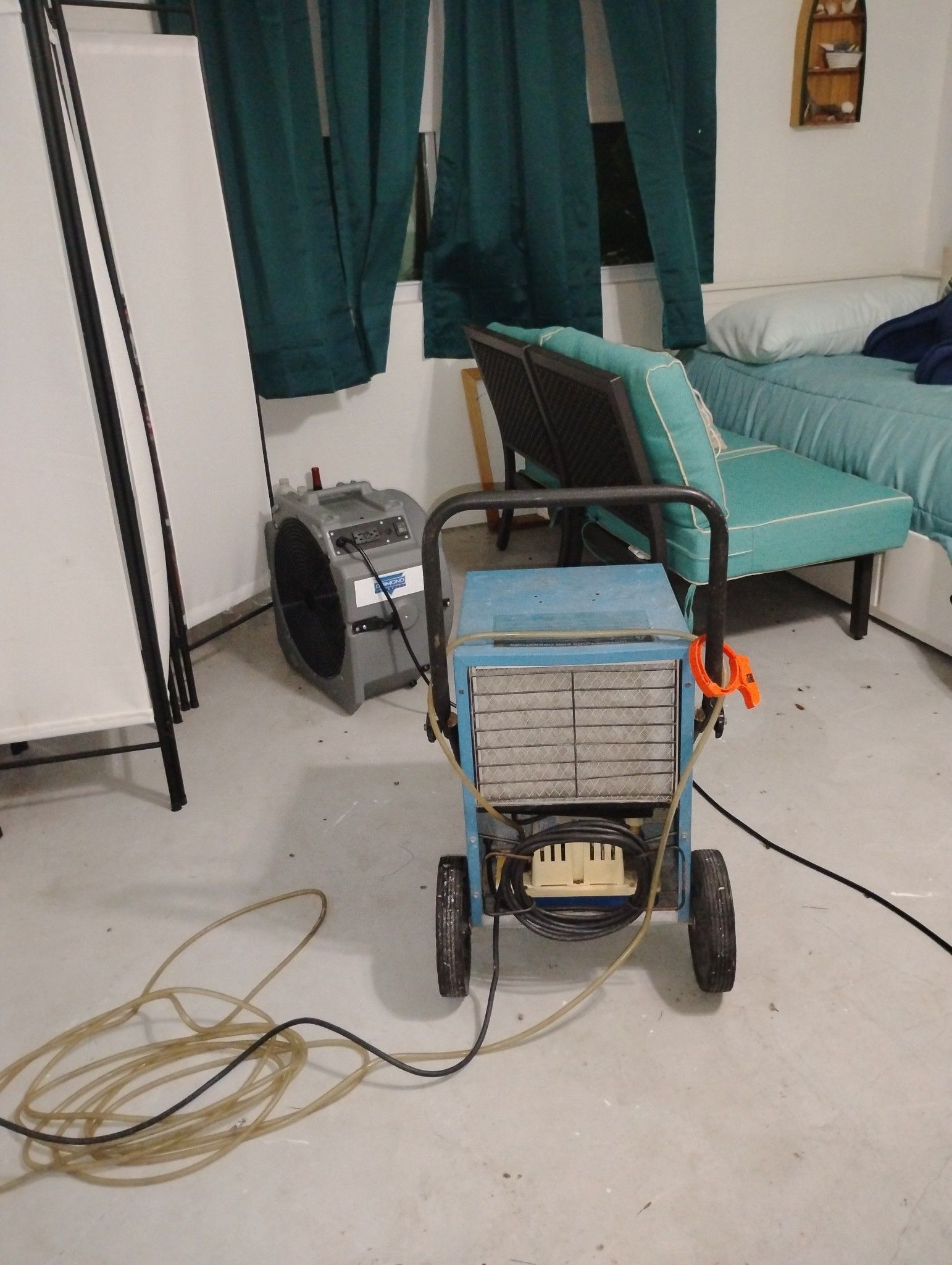 A room with a bed and a chair and a machine on the floor