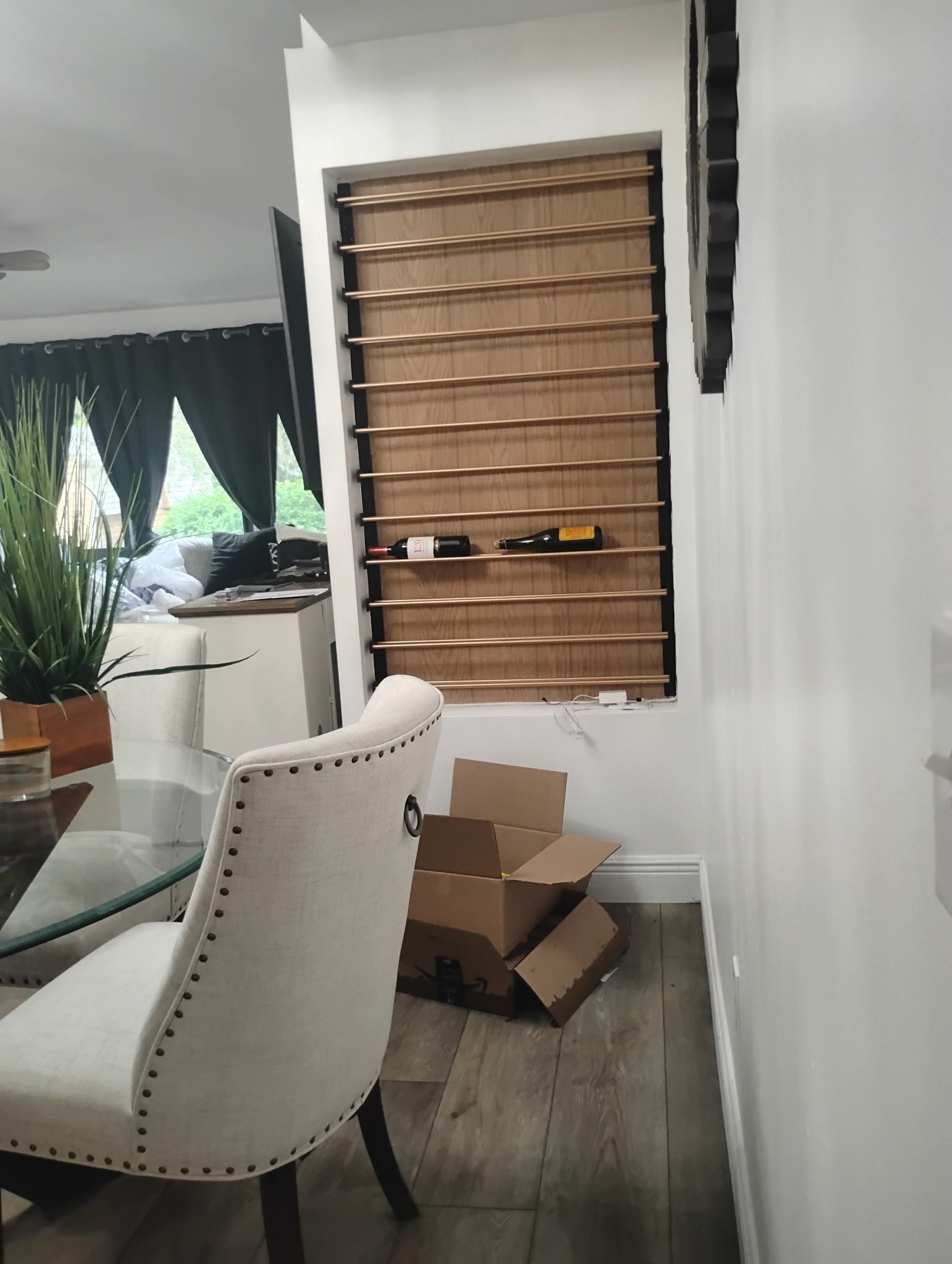 Dining room with a glass-top table and upholstered chair. A window with bronze-colored blinds is in the wall.