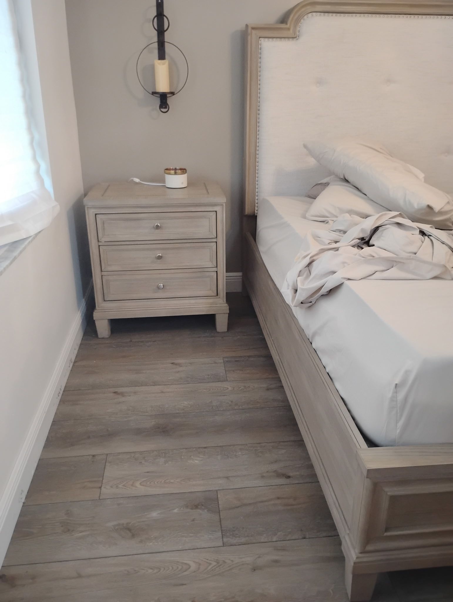 Bedroom corner with a gray nightstand, bed, and gray flooring.