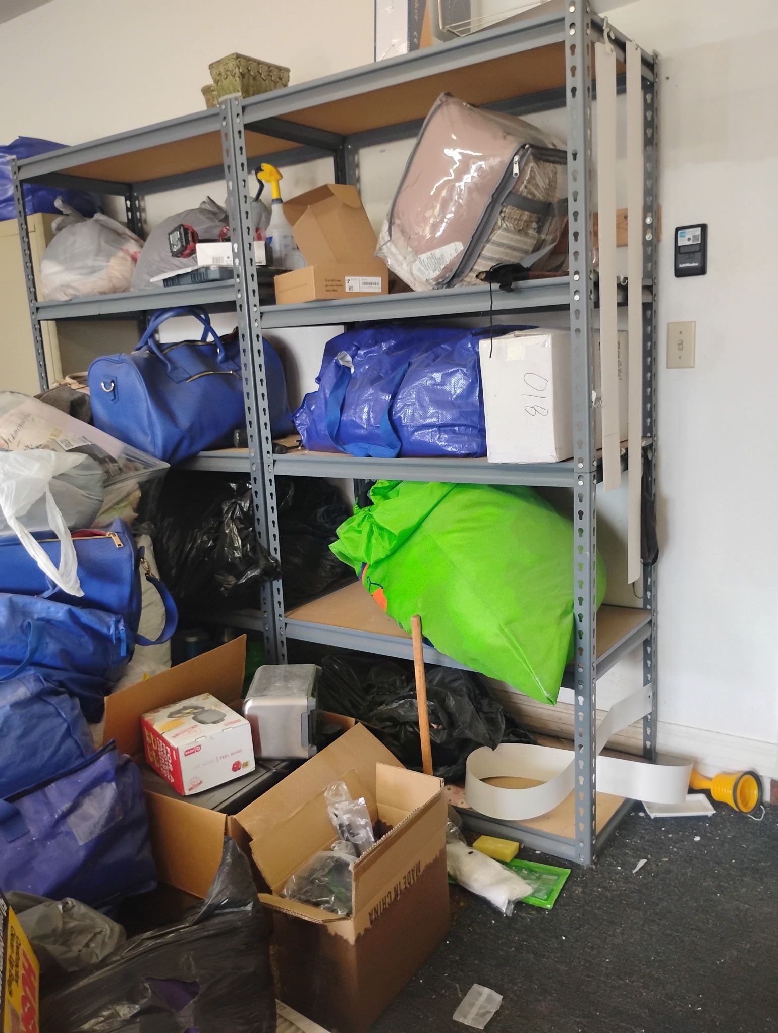 Shelving unit overloaded with various items in a garage: bags, boxes, and other objects.