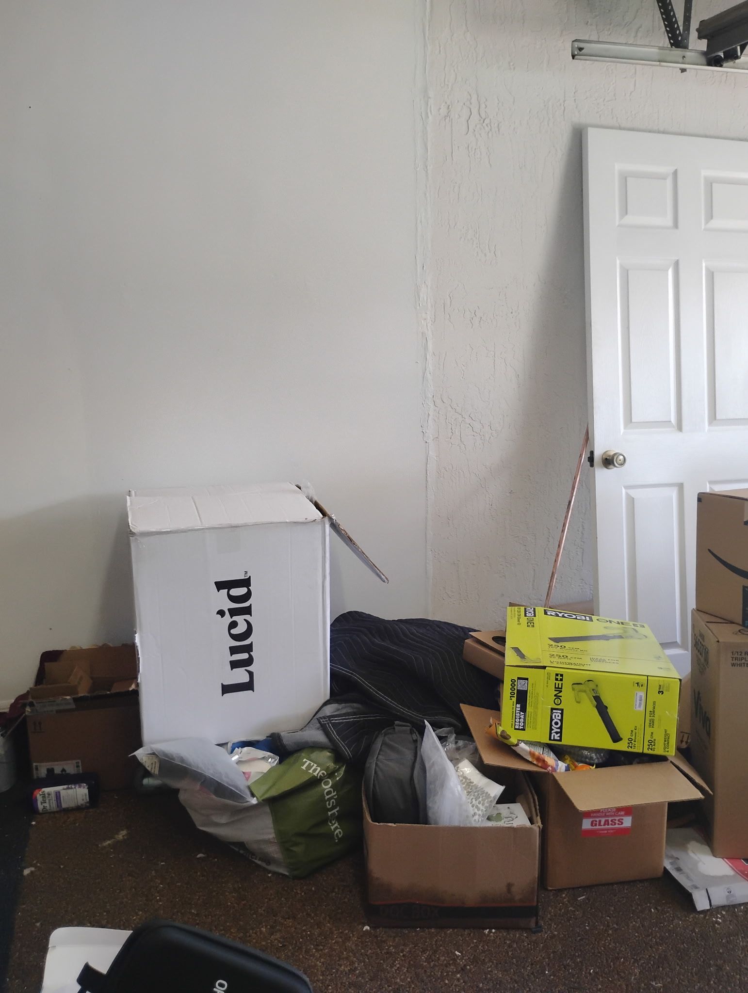 Boxes and clutter against a white wall and door in a room.