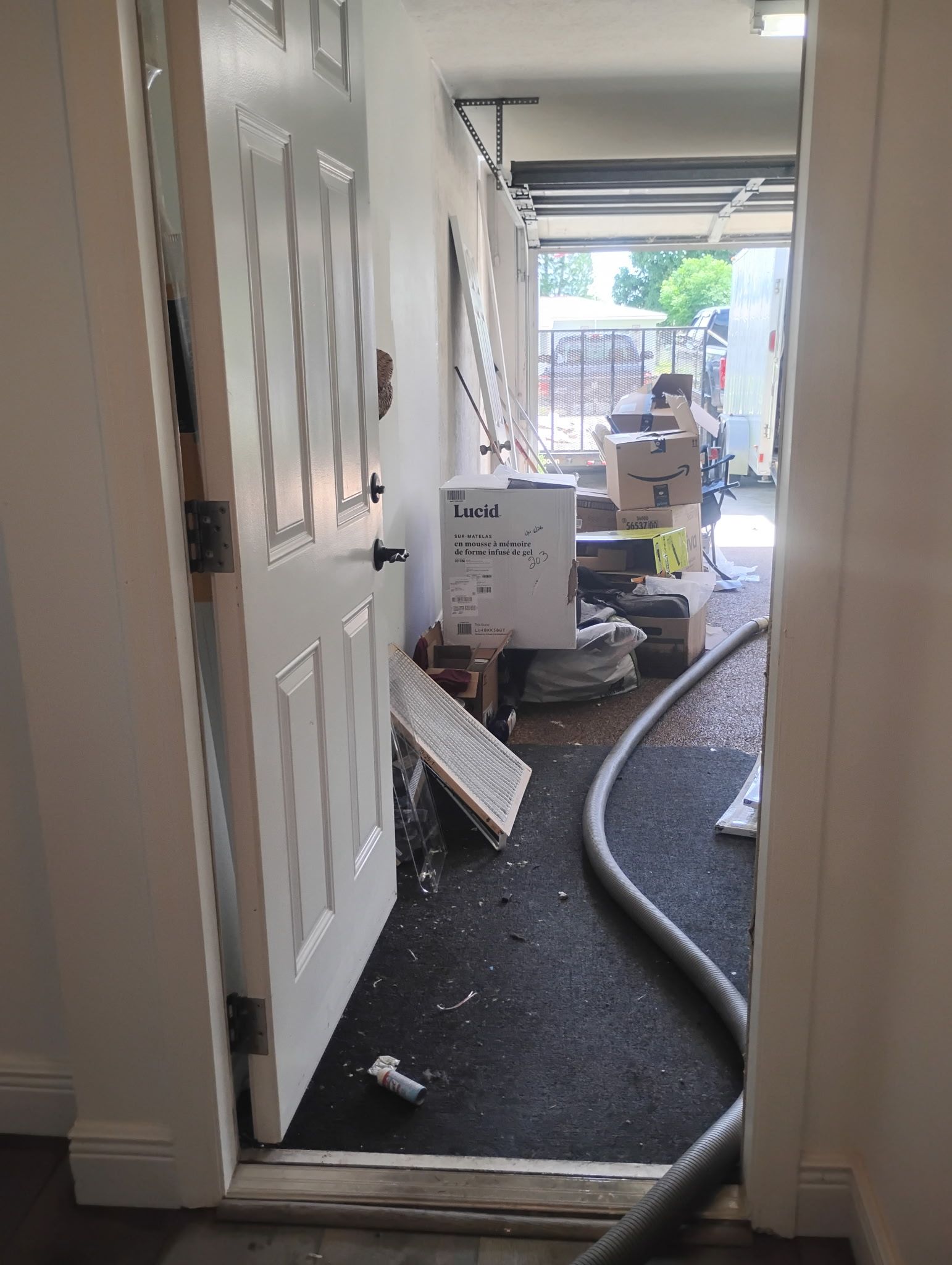 Open doorway showing a cluttered interior during renovation: debris, boxes, and a hose.