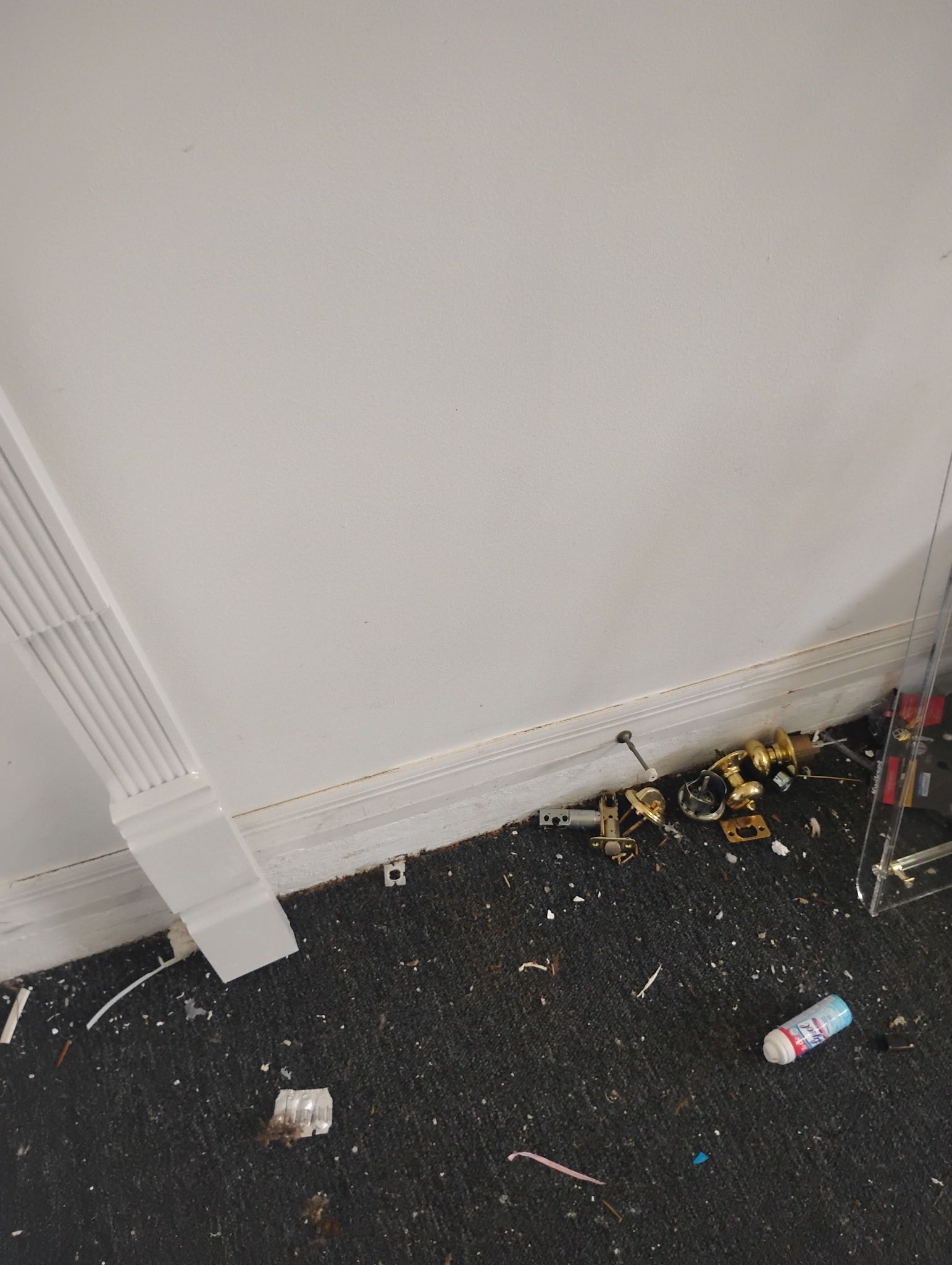 White fabric attached to a dark floor, with debris including hardware and a spray can.