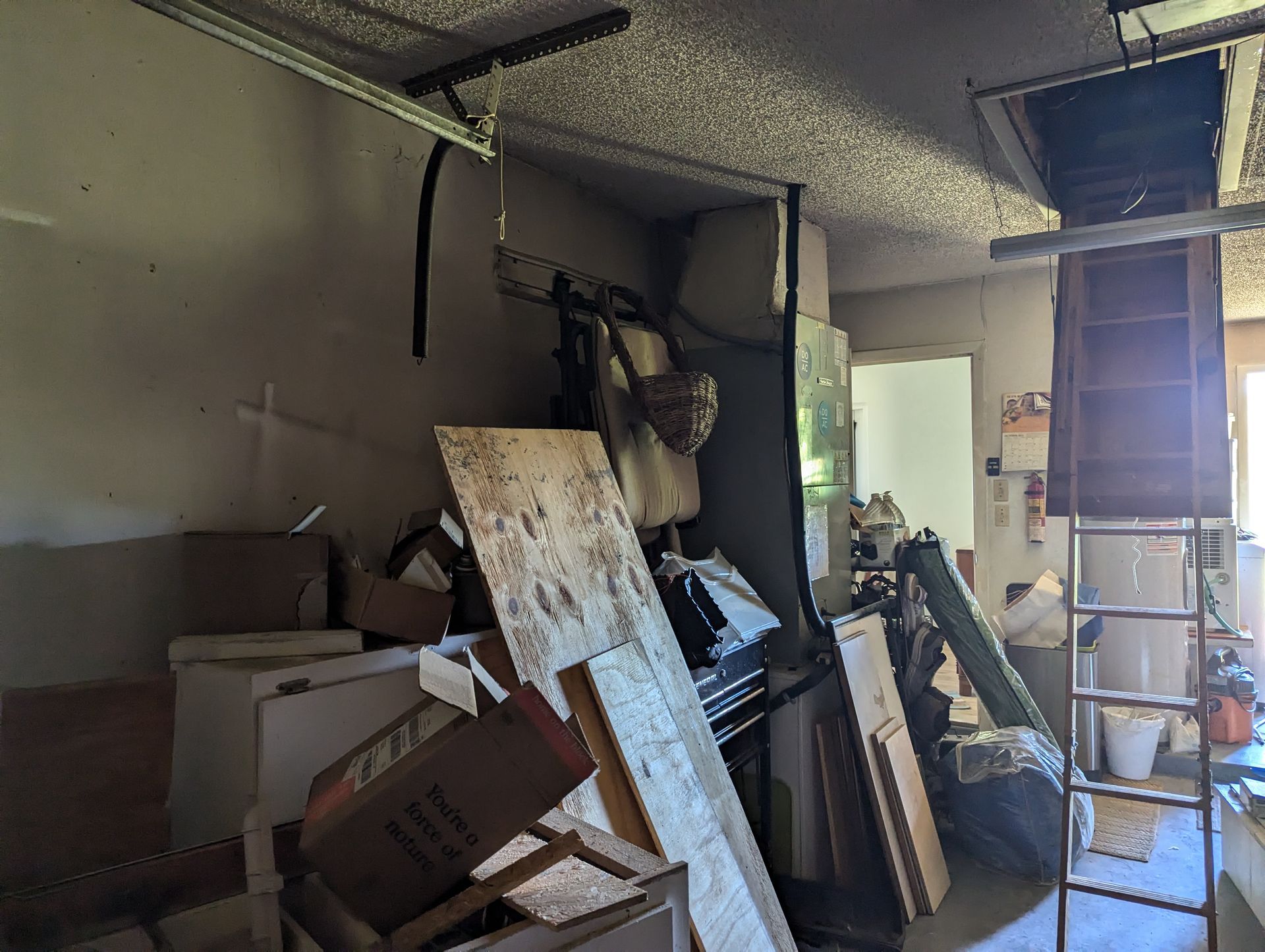 A garage filled with lots of junk and a ladder.