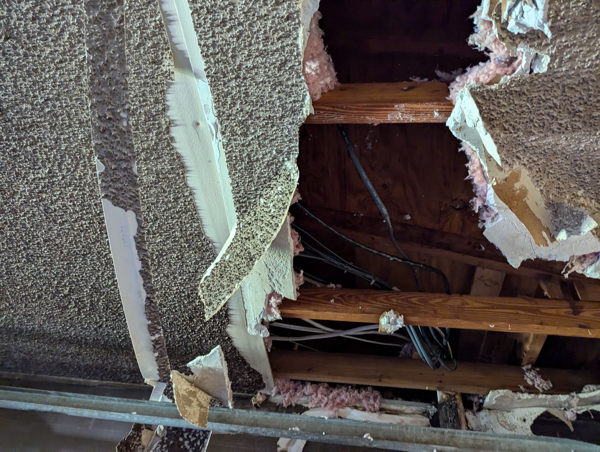 A ceiling with a hole in it and a lot of damage to it.