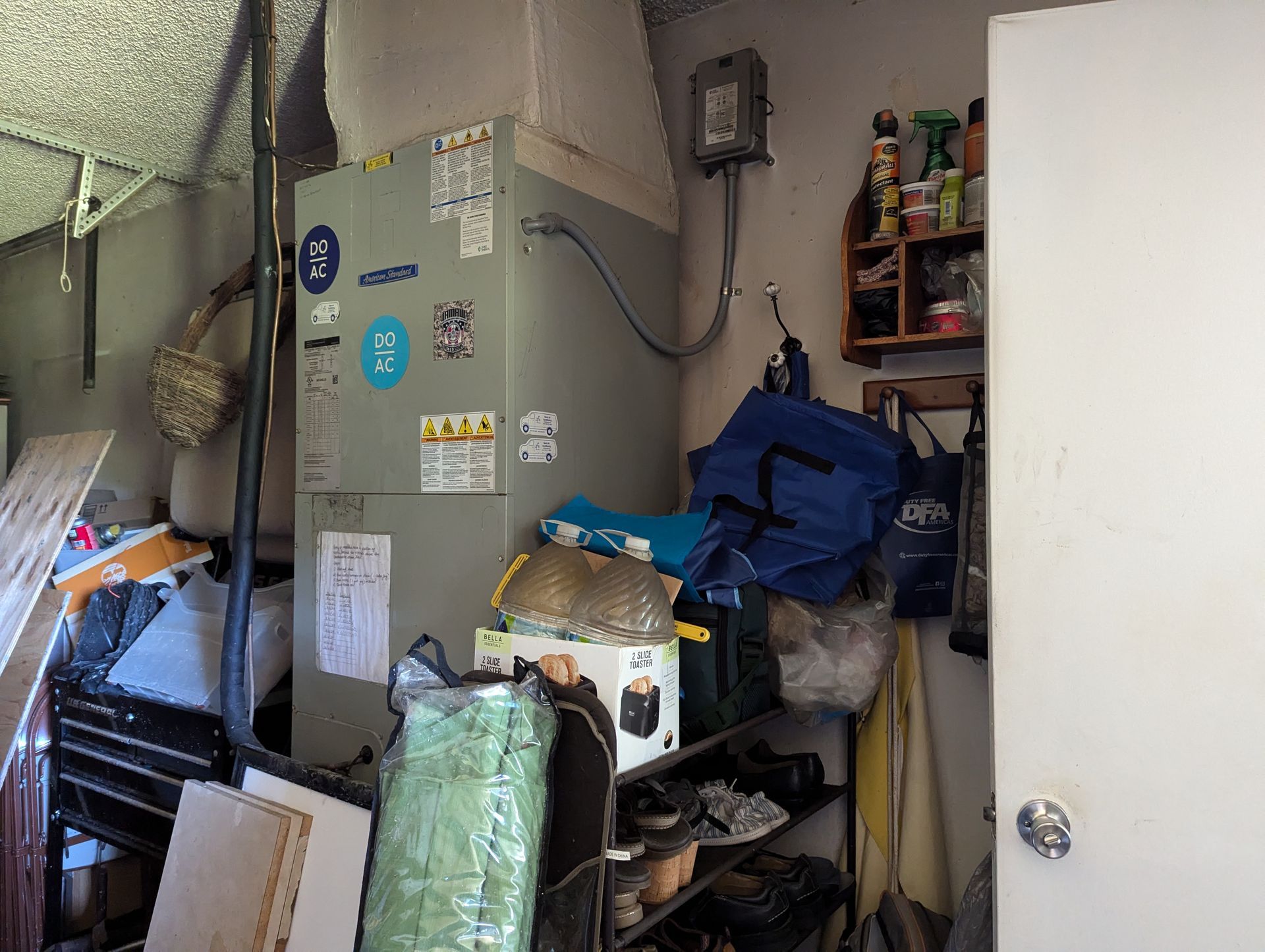 A messy room with a fridge and a door.