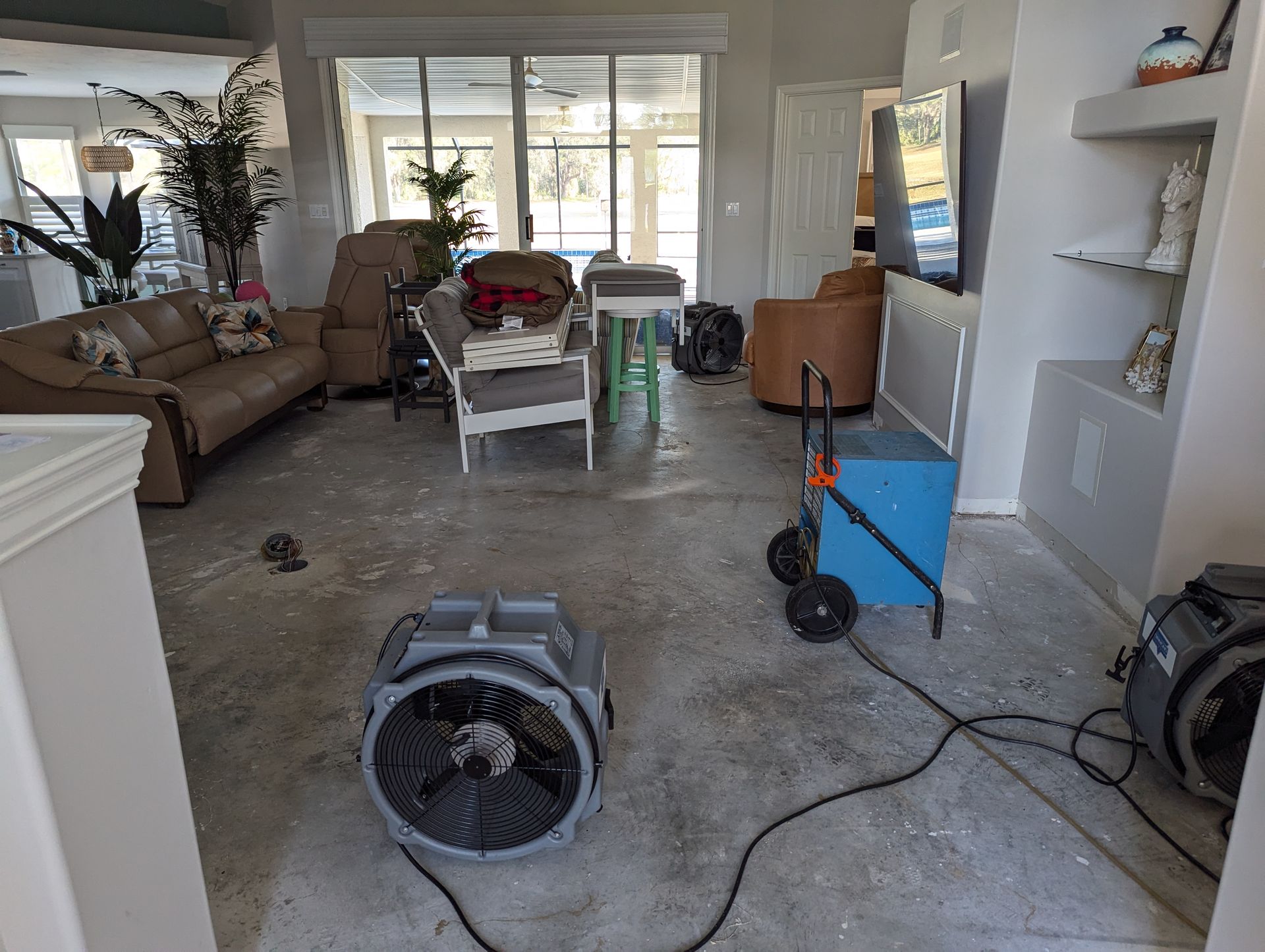 A living room with a couch and chairs and a fan on the floor.