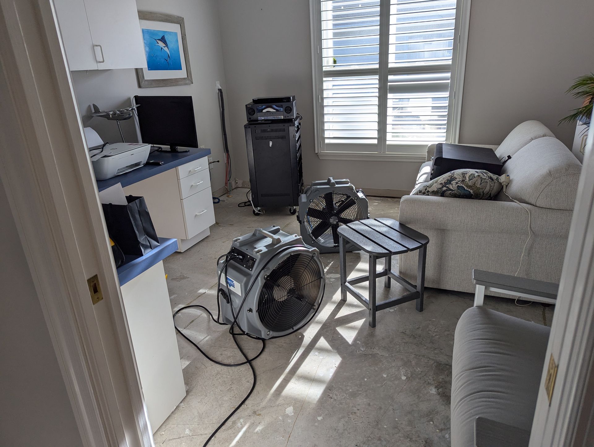 A living room with a couch and a fan on the floor.