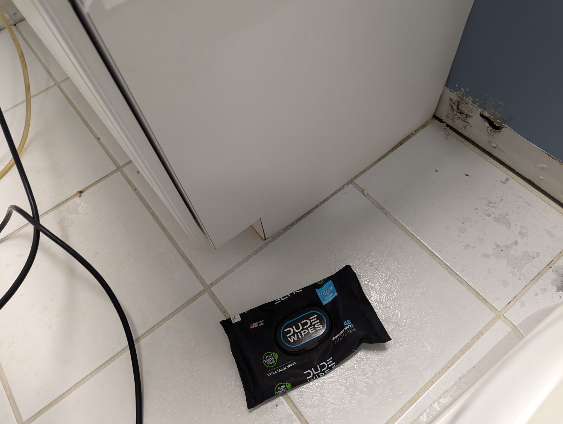 A pack of wipes is sitting on a tiled floor in a bathroom.