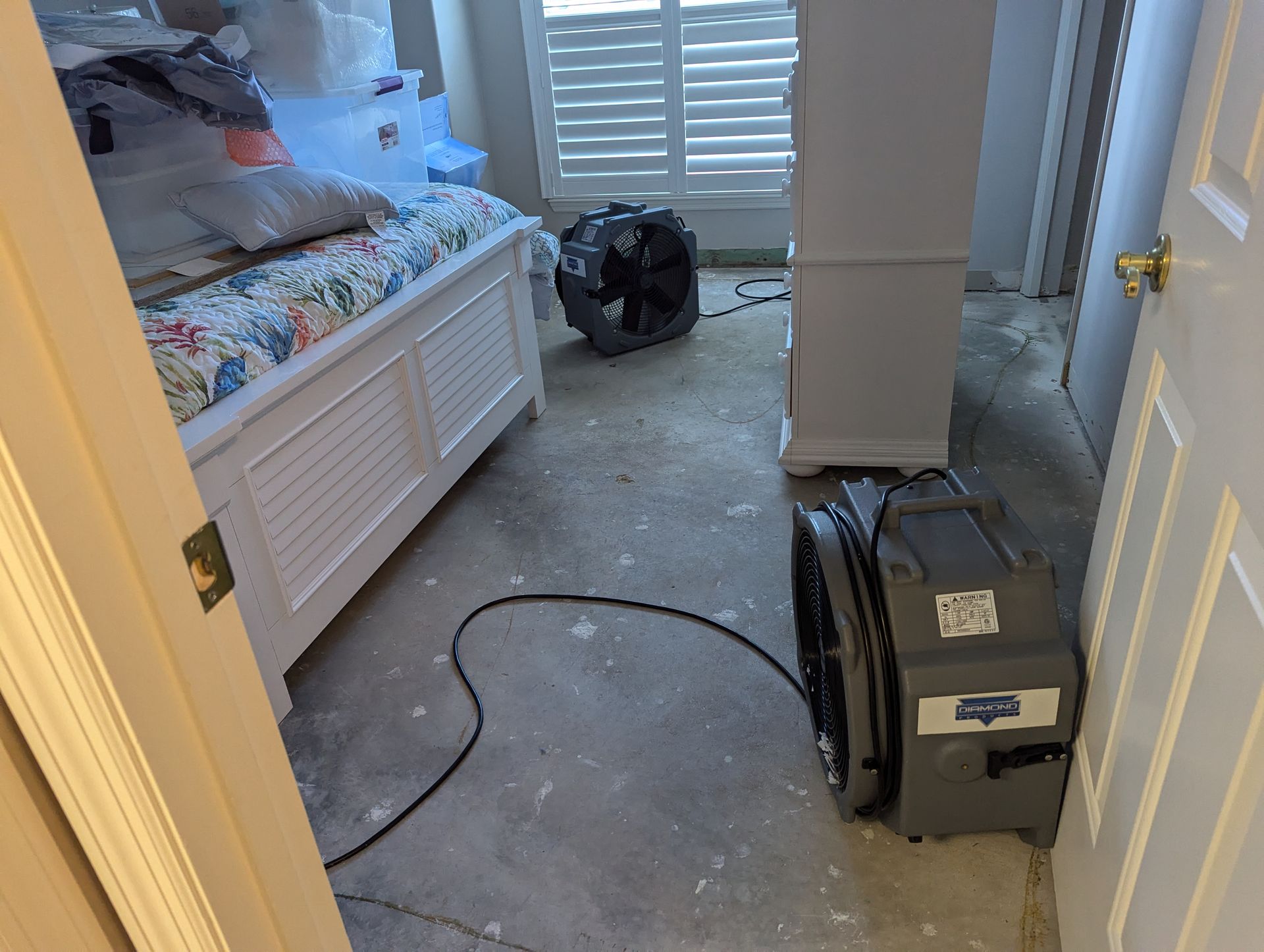 A bedroom with a bed and a fan on the floor