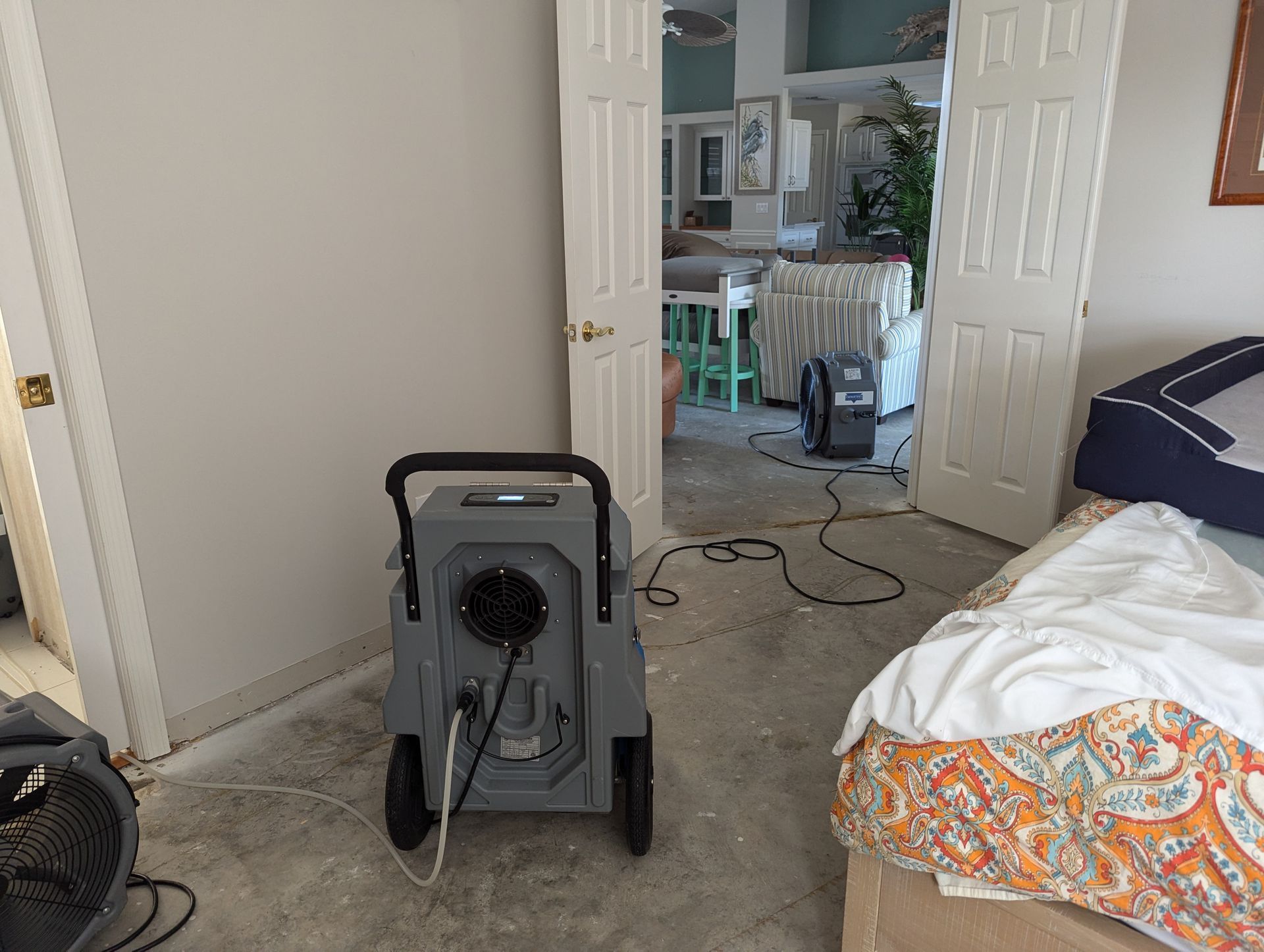 A bedroom with a bed and a vacuum cleaner in the corner.