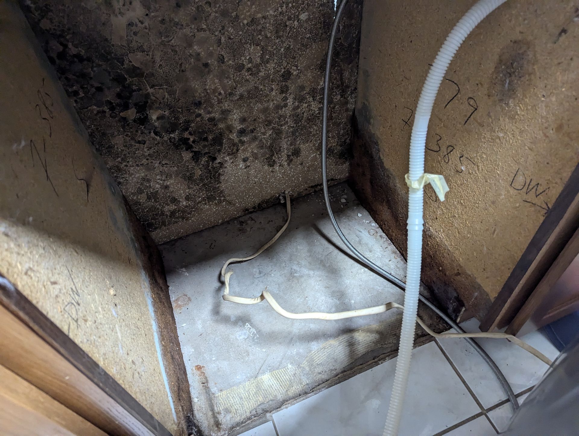 A dirty room with a hose and wires coming out of it.