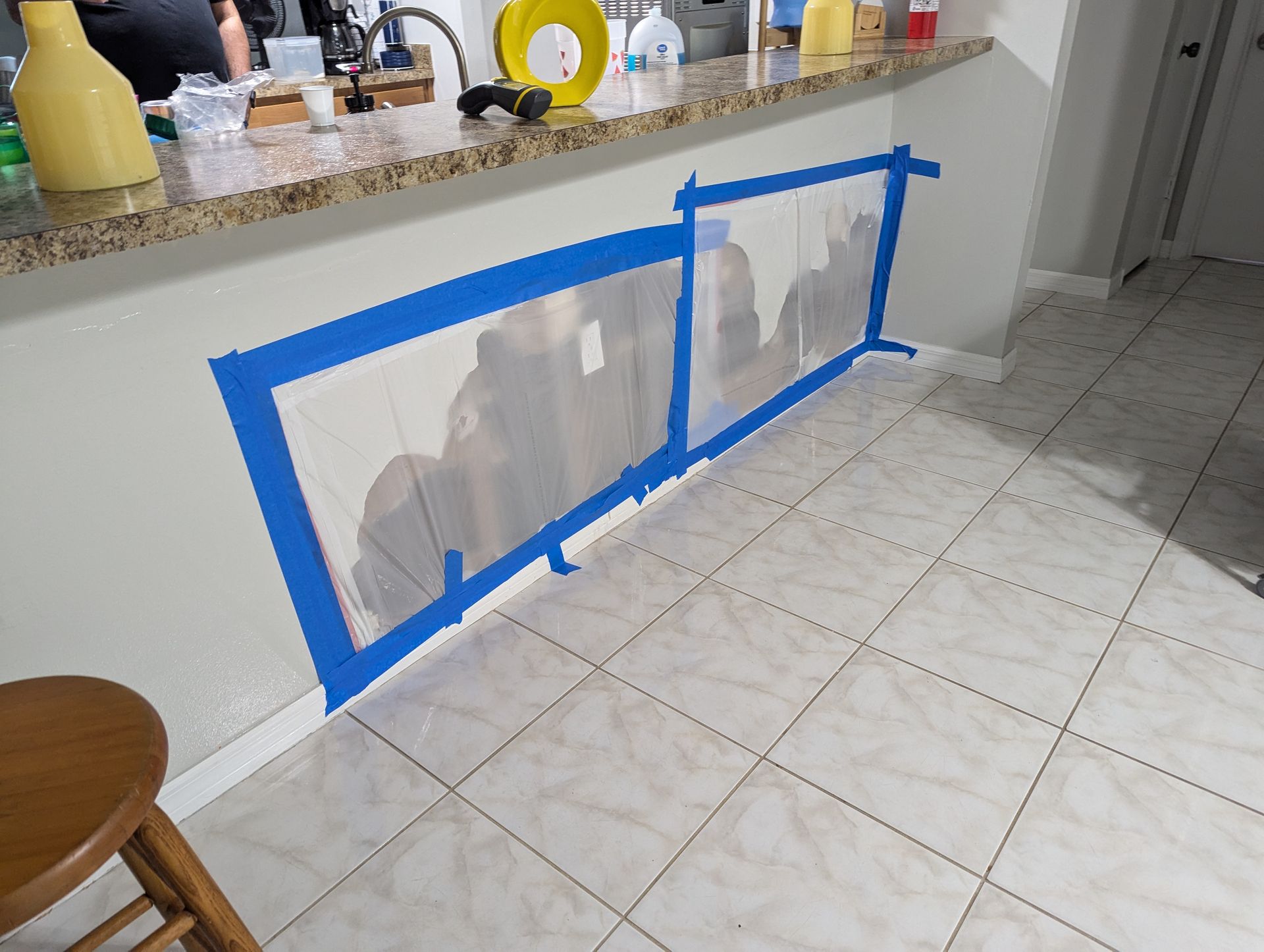 A kitchen counter is taped to the wall with blue tape