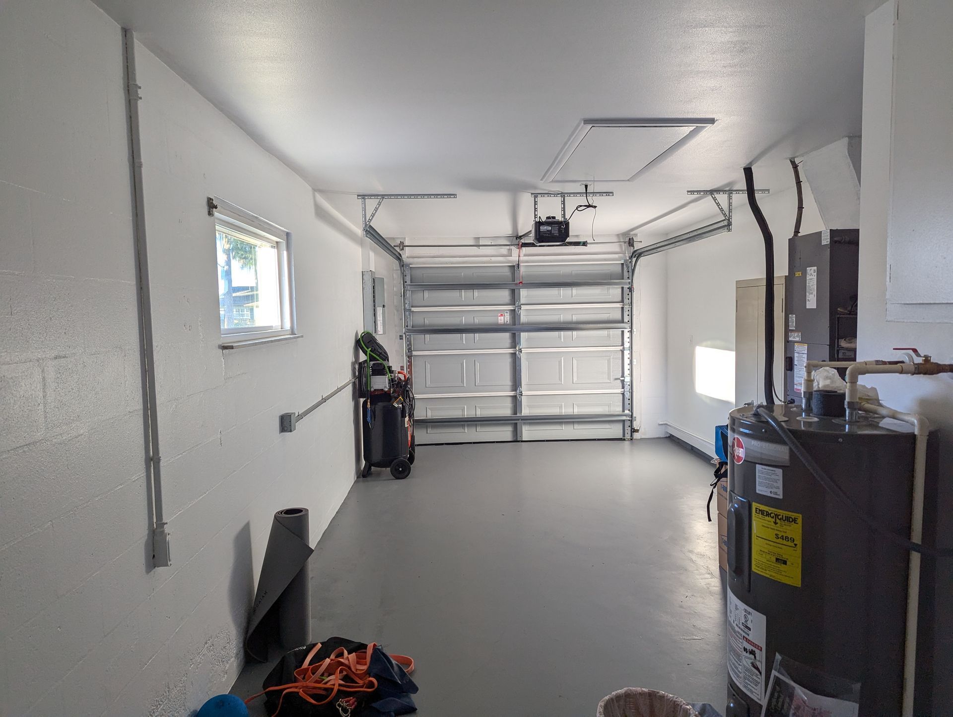A garage with a garage door open and a water heater.