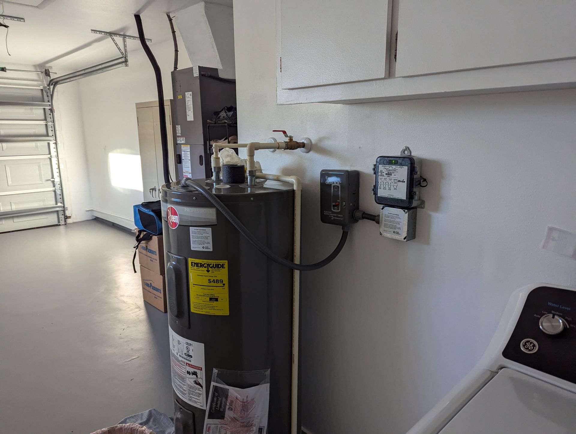 A water heater is sitting in a laundry room next to a washer and dryer.