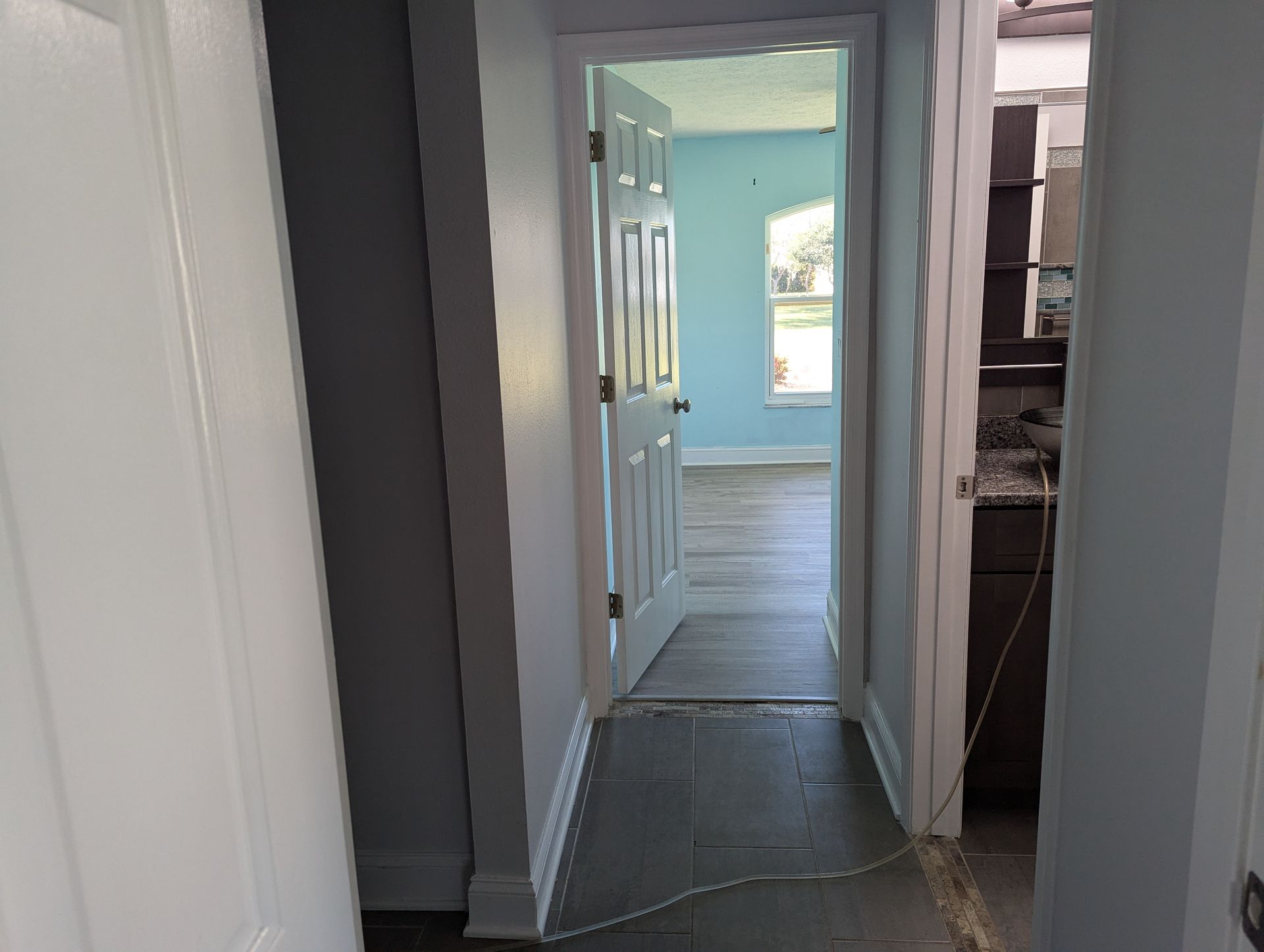 A hallway in a house with a door open leading to a room.