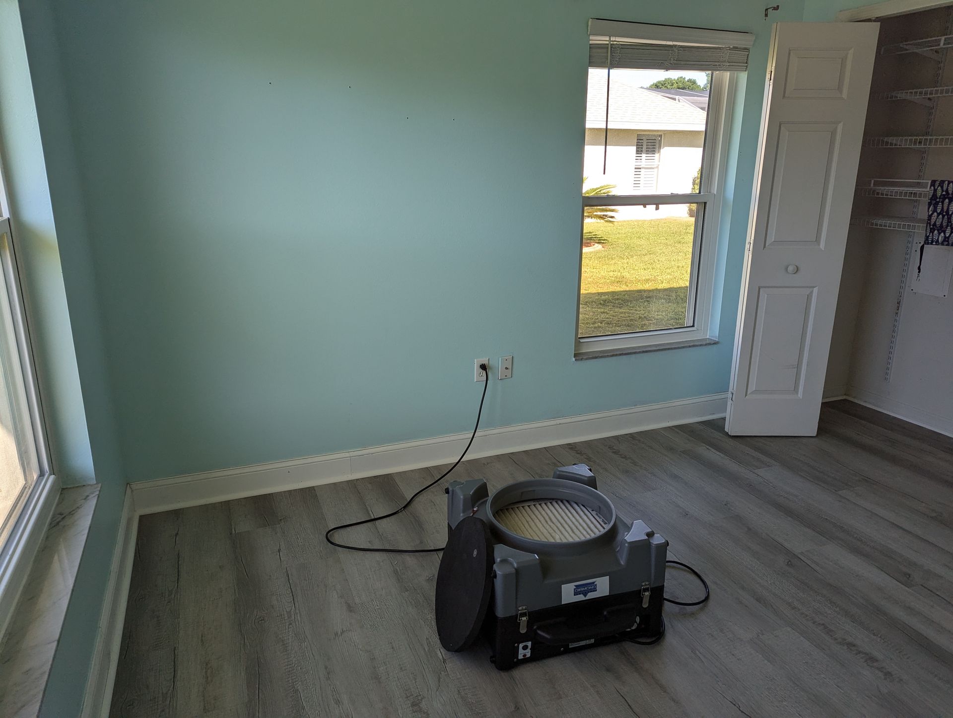 A room with a vacuum cleaner sitting on the floor in front of a window.