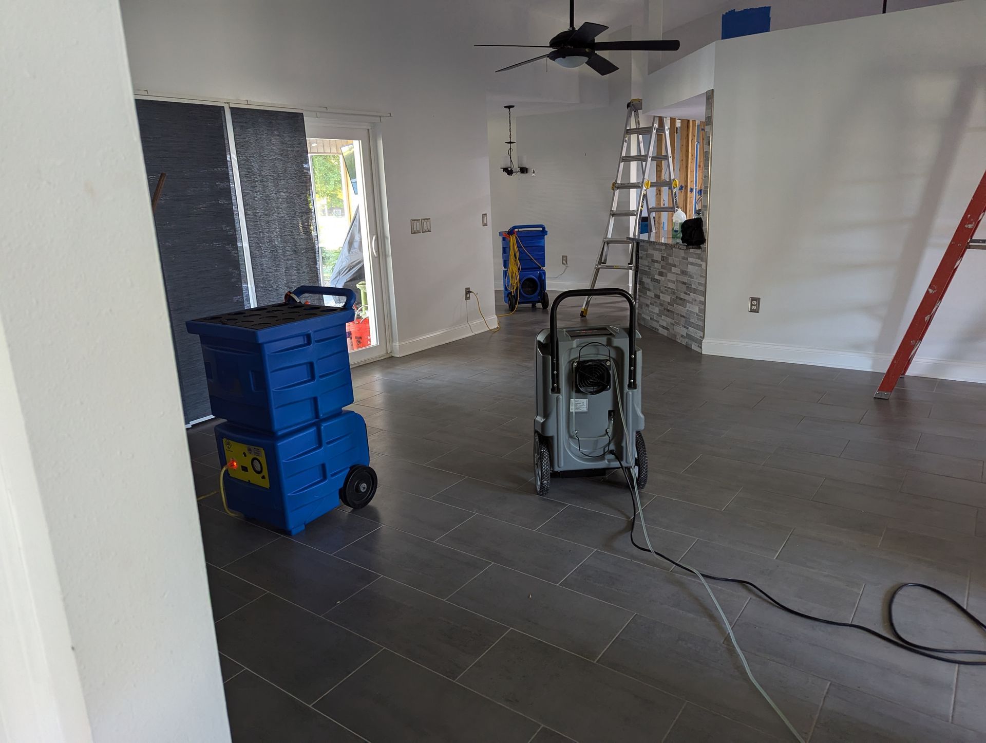A room with a ceiling fan and a vacuum cleaner on the floor.