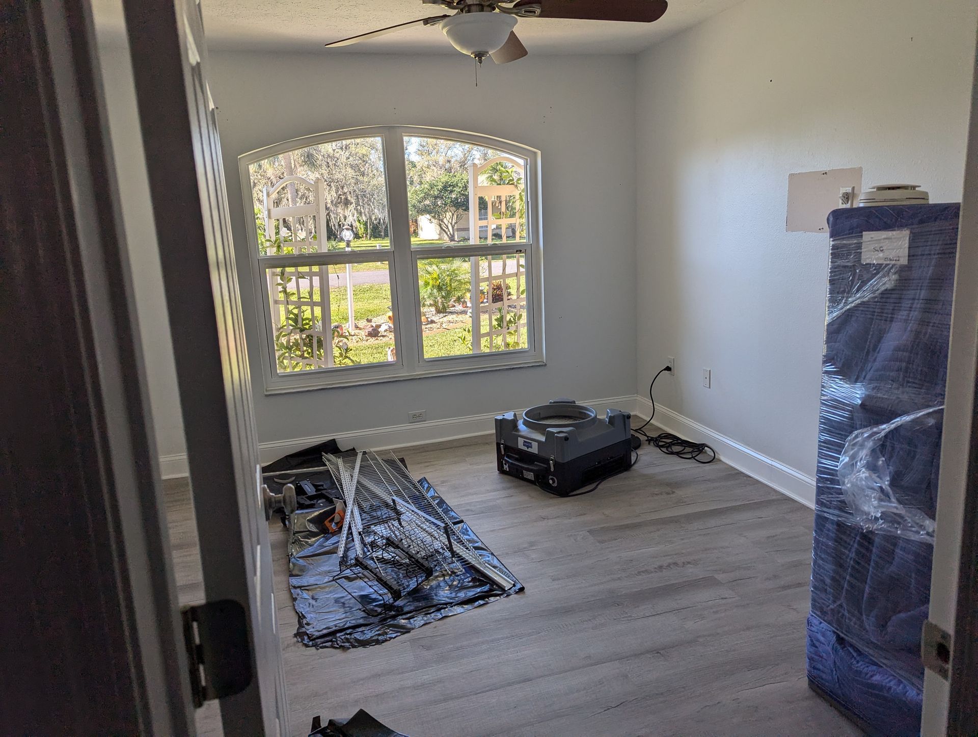 An empty room with a ceiling fan and a window.