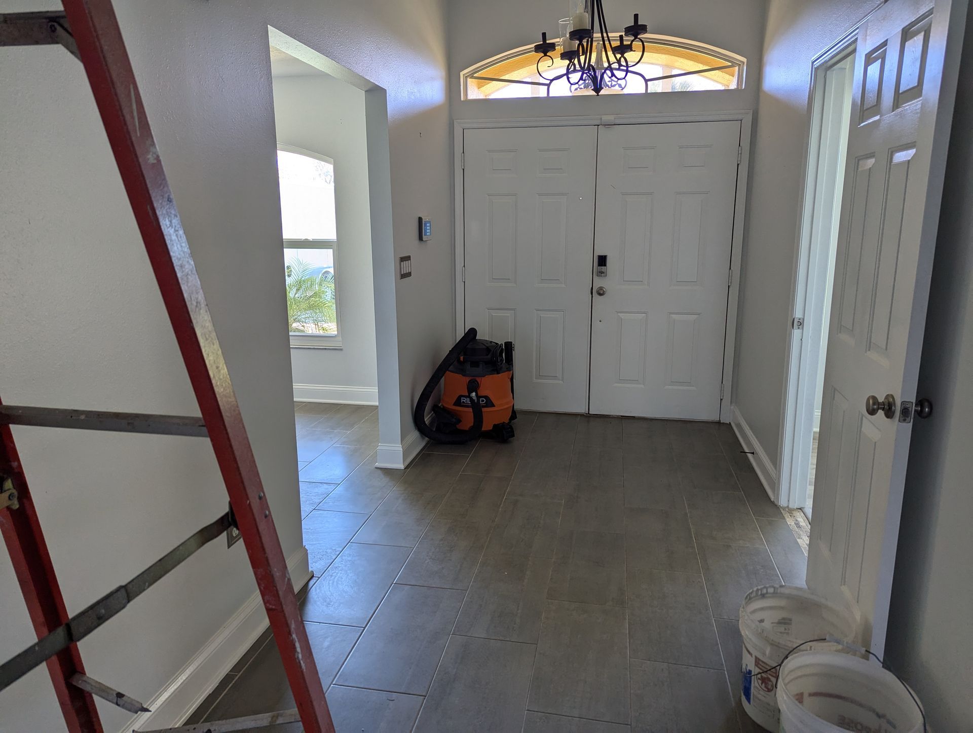 A hallway with a ladder and a vacuum cleaner in it.